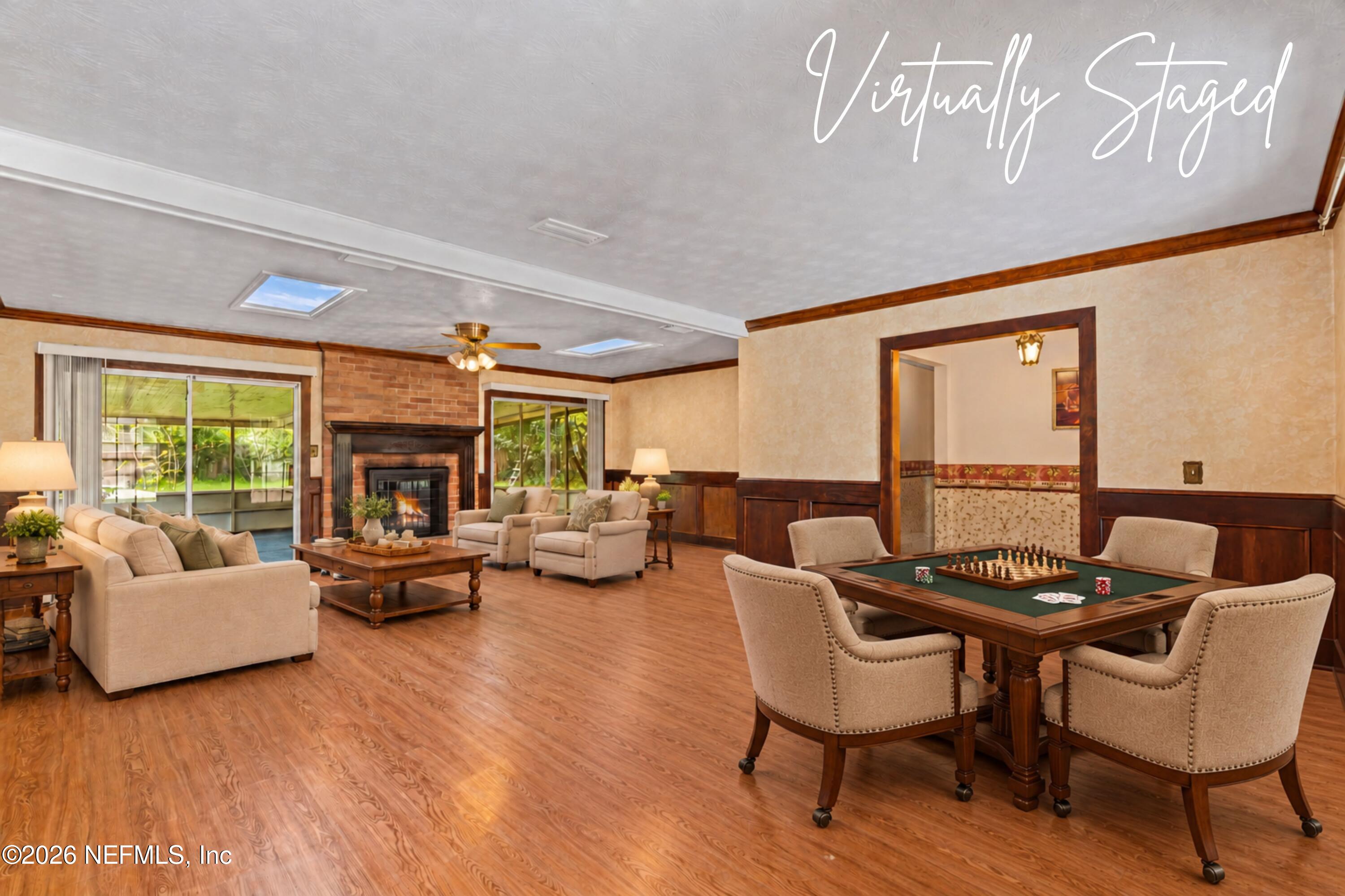 Virtually staged living room with a brick fireplace, sliding glass doors, and a game table.