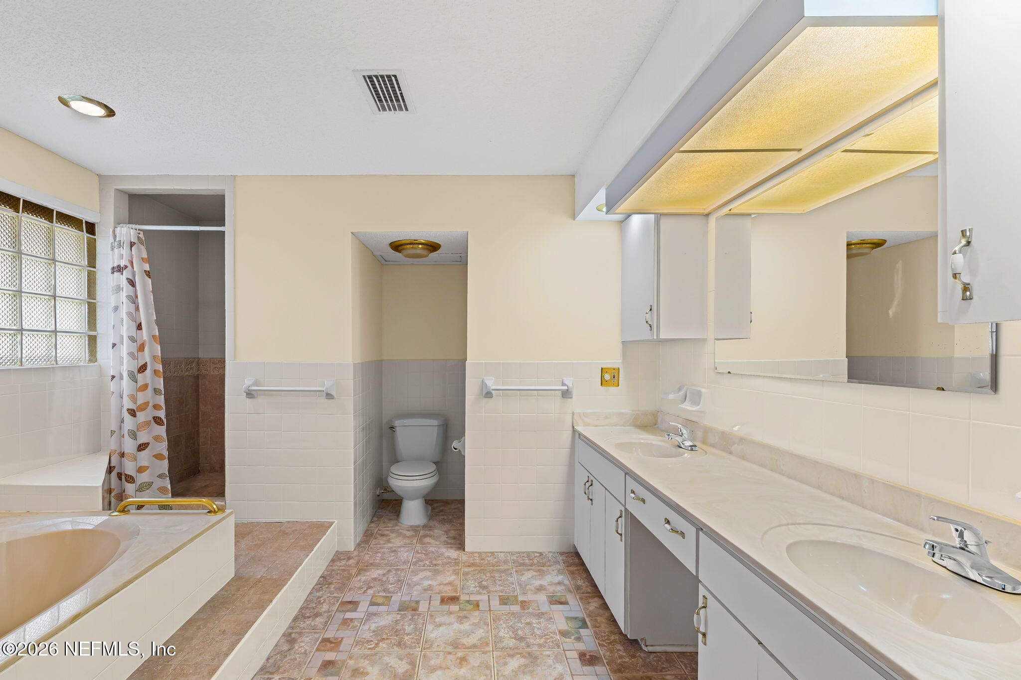 Bathroom with double vanity, bathtub, glass-block window, and a separate shower area.
