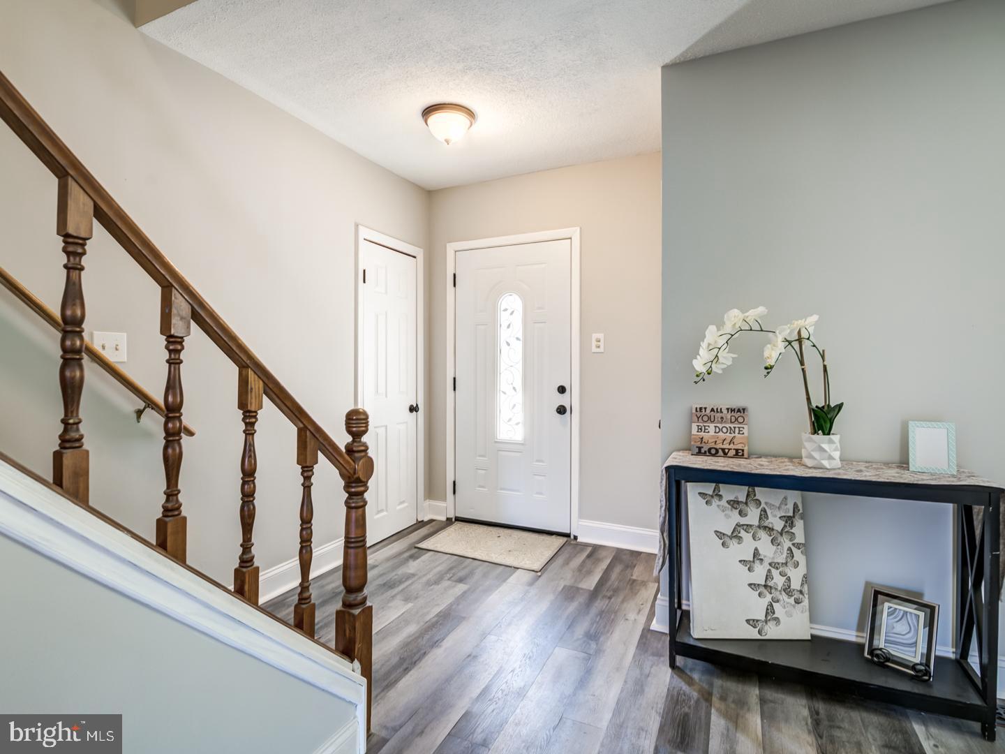 Entryway with a dark wood staircase, white front door, and console table topped with an orchid.