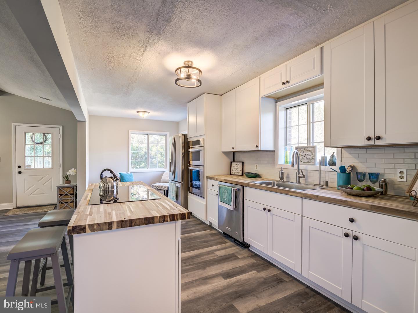 Kitchen with white cabinets, stainless steel appliances, and a large butcher-block island with seating.