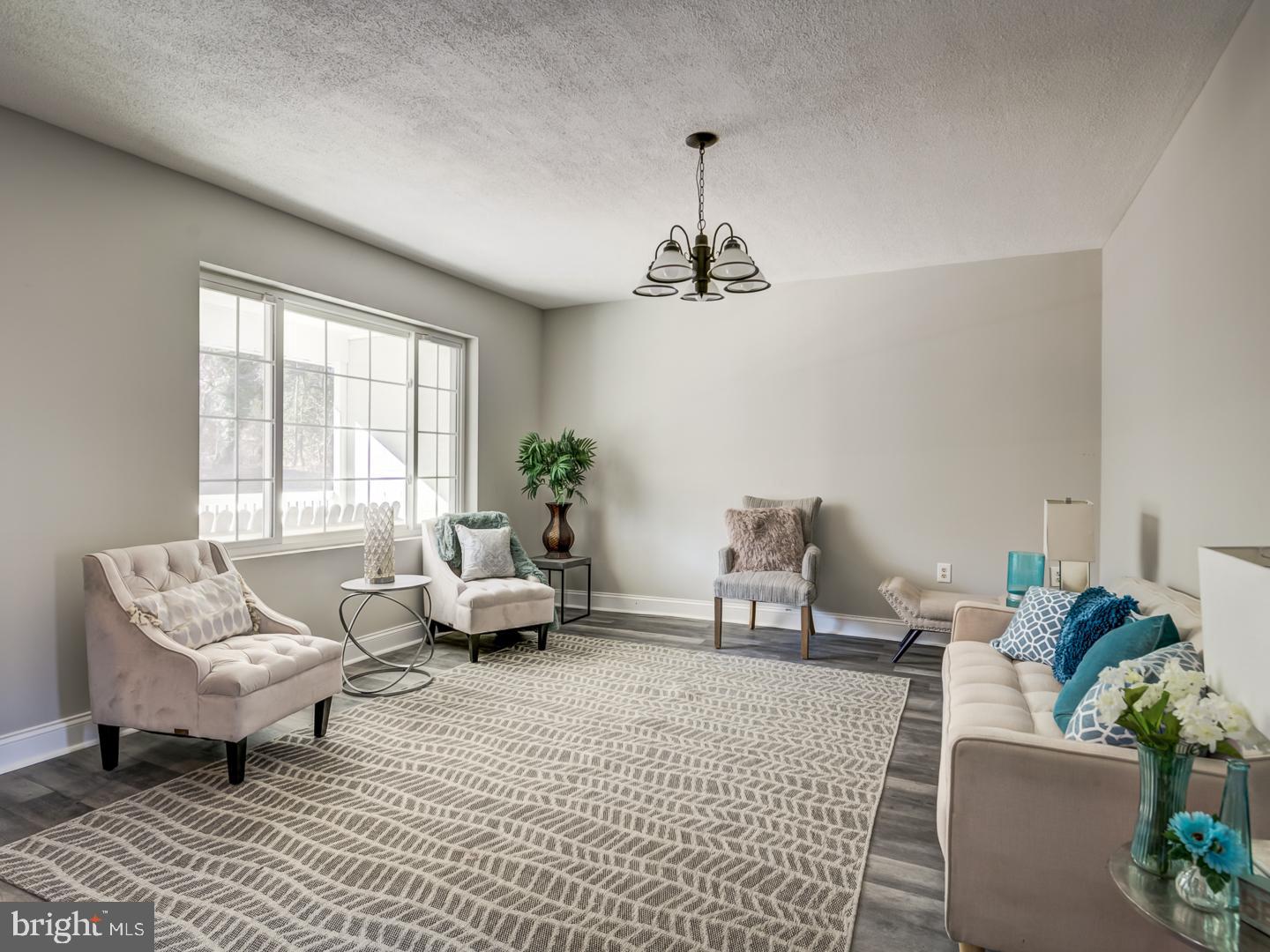 Staged living room with pale seating, a patterned rug, and a large gridded window.
