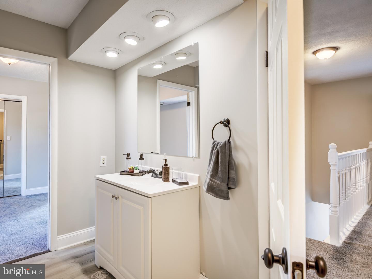 Bathroom vanity with a large mirror and gray towel beside an upstairs landing.