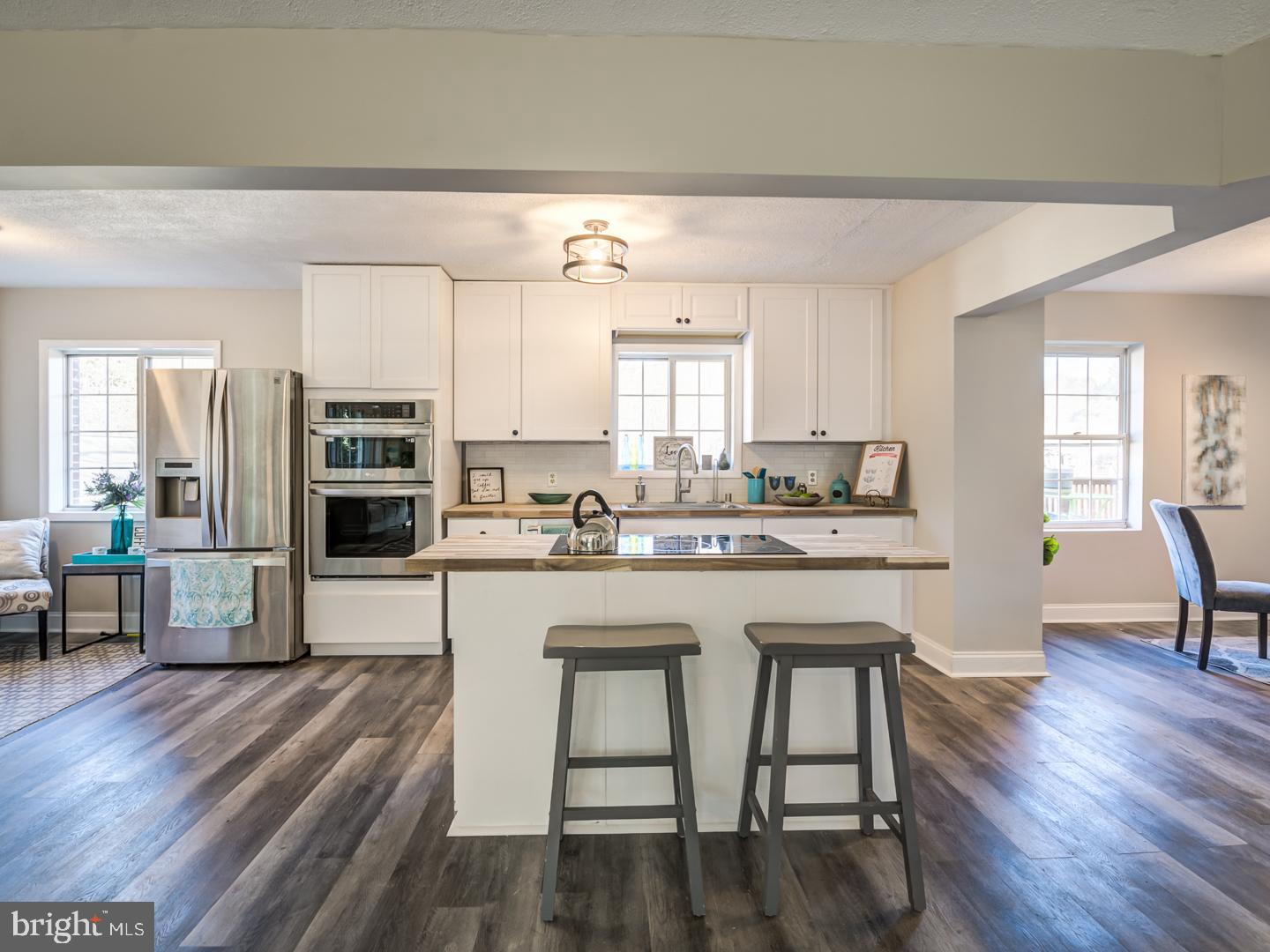 Kitchen with white cabinets, stainless steel appliances, and a large island with two stools.