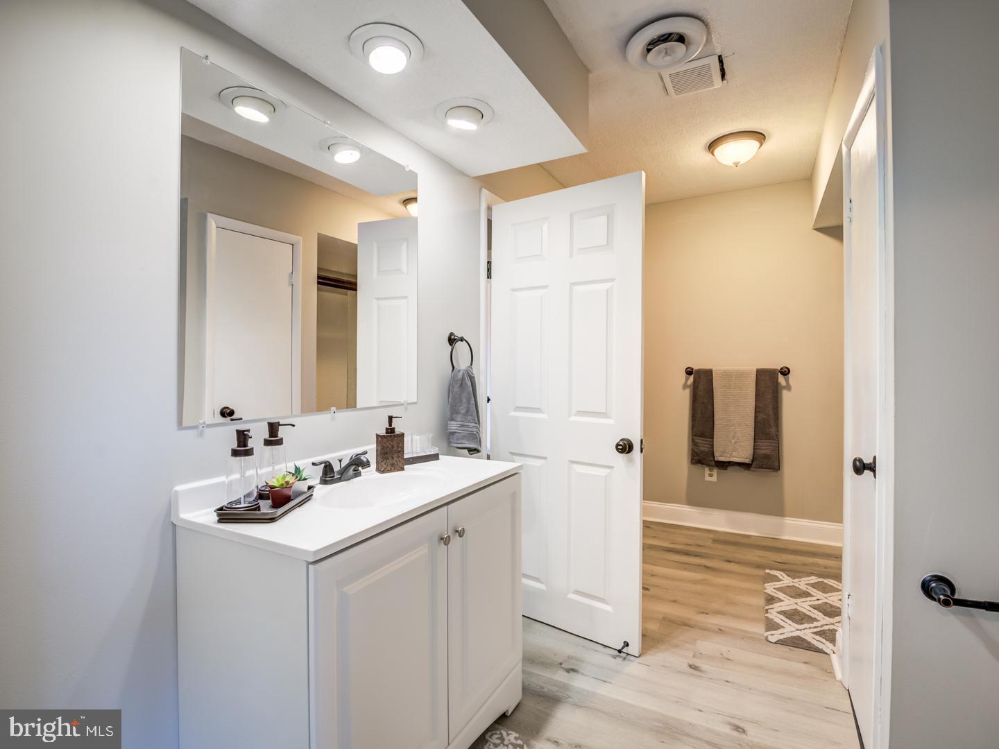 Bathroom with a white vanity and wide mirror beside an open doorway.