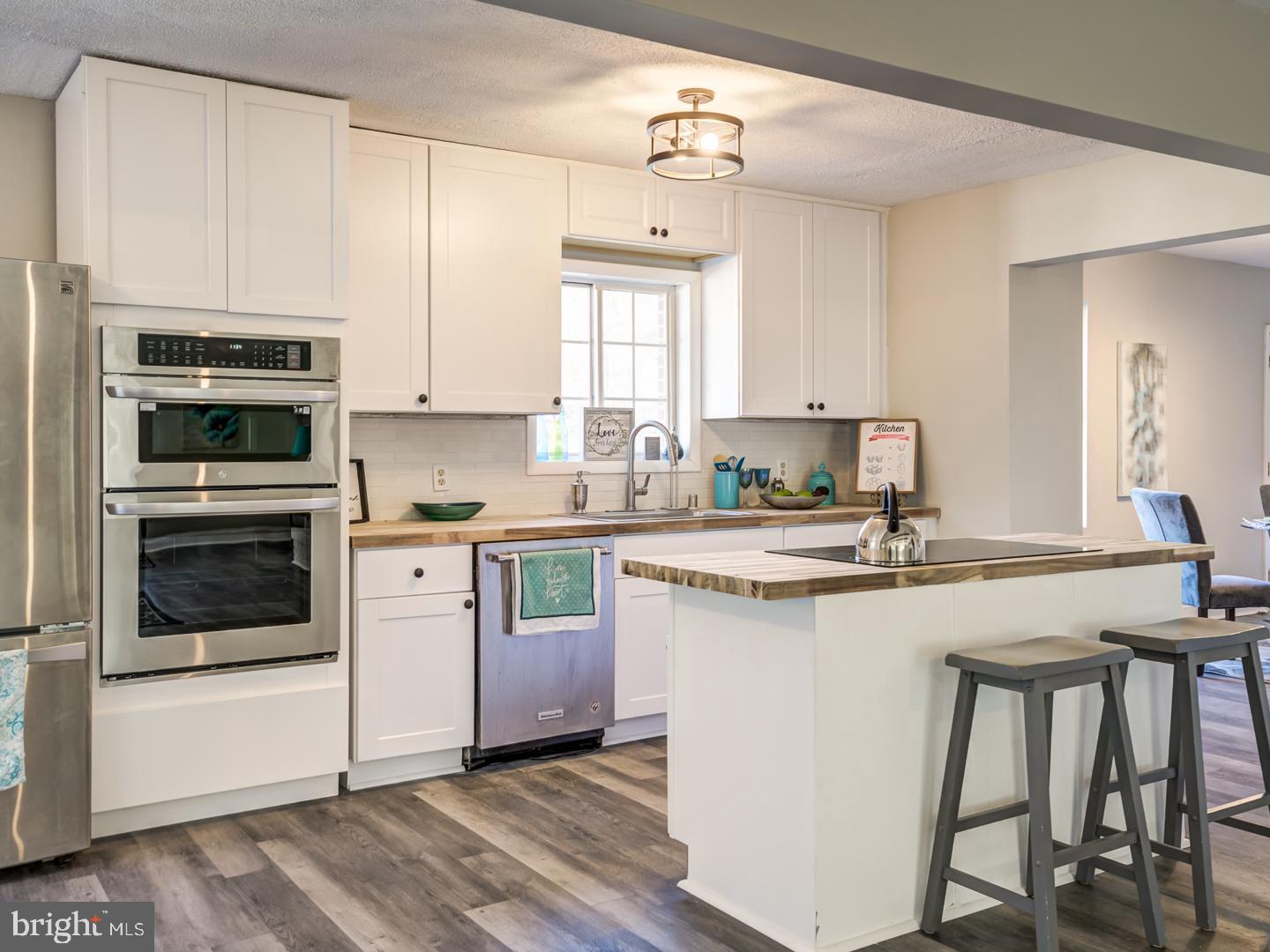 Kitchen with white shaker cabinets, stainless steel appliances, and a large island with bar stools.