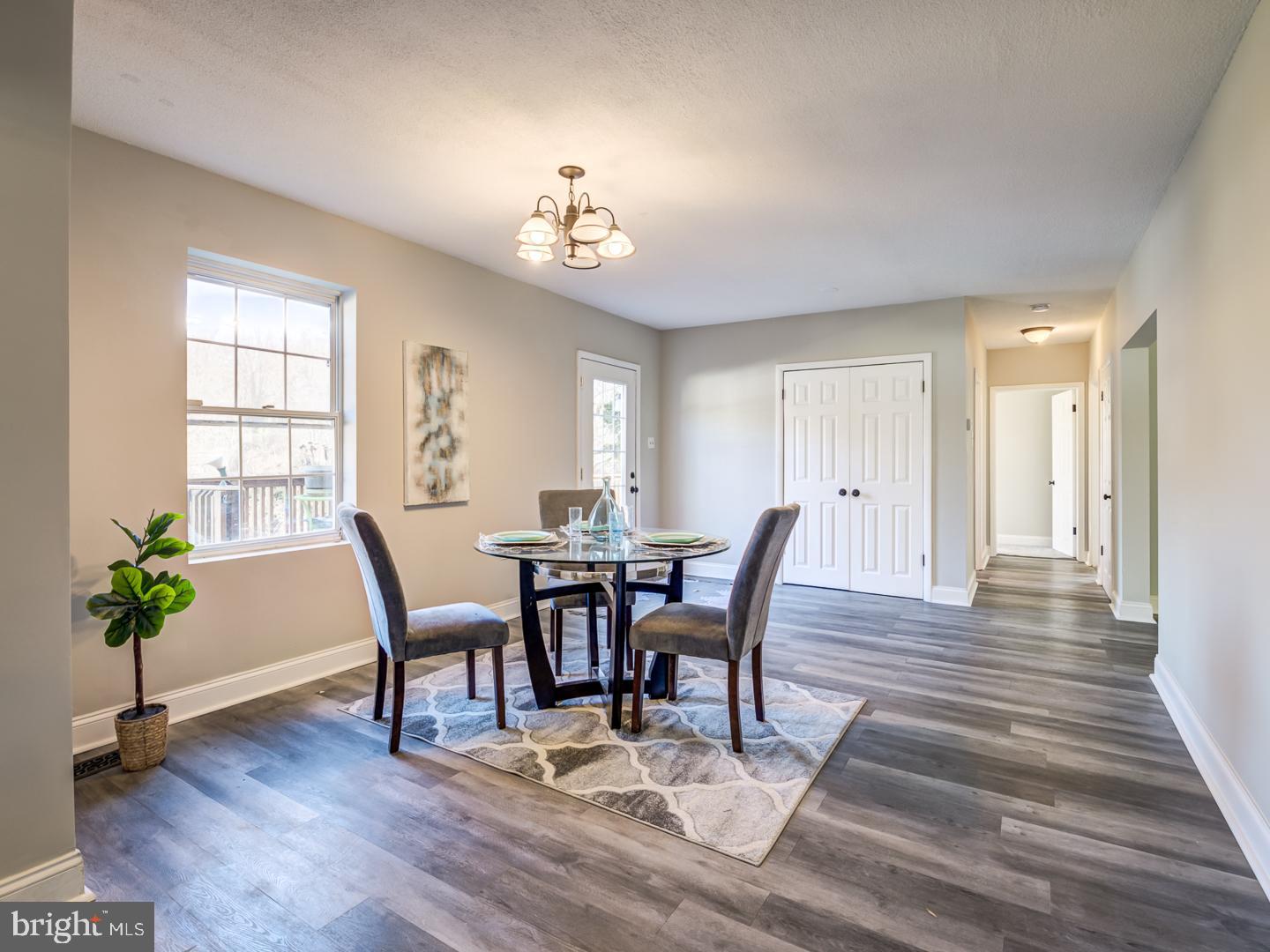 Dining room with a round table and chairs on a patterned rug beside a large window.