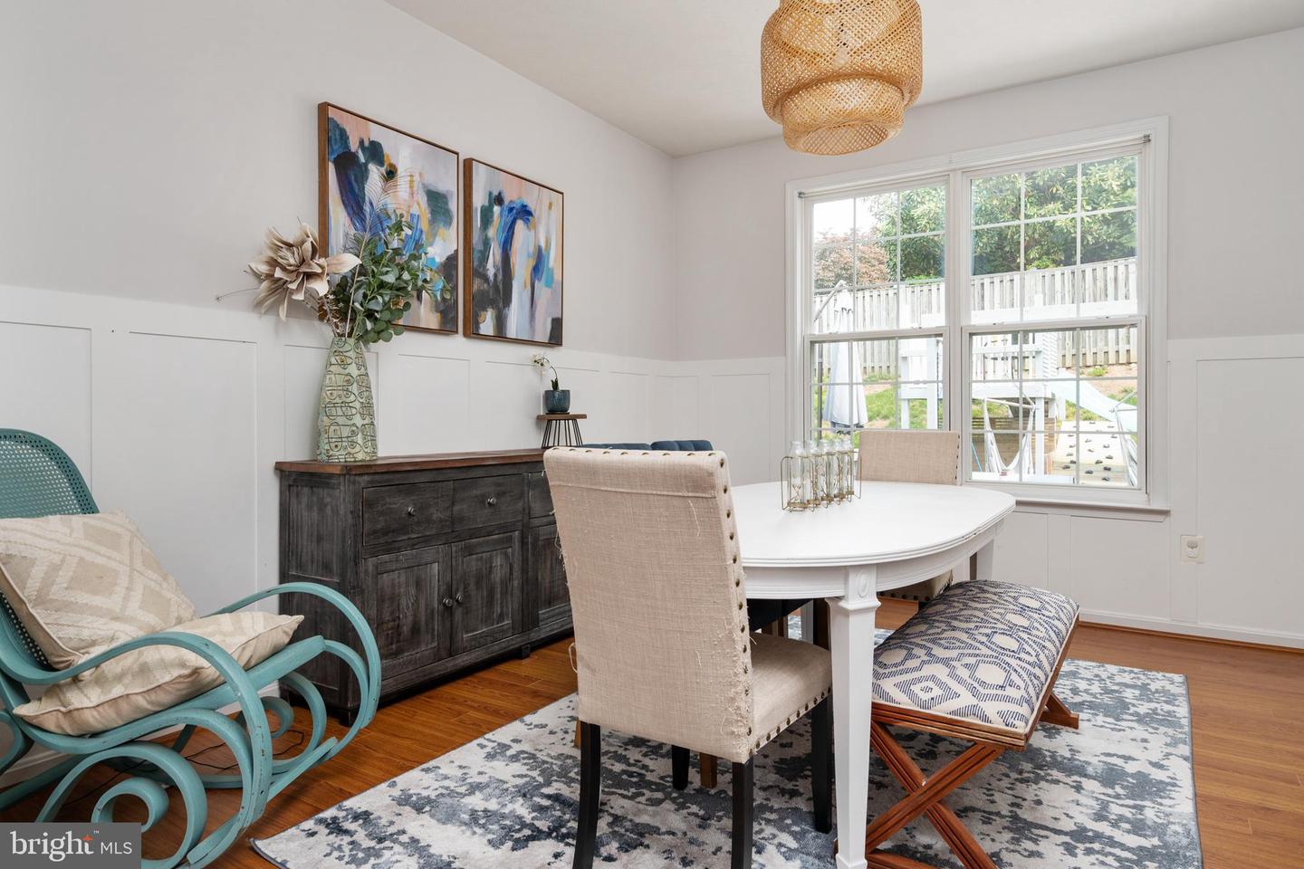 Dining room with a white oval table, dark sideboard, and large windows overlooking a deck.