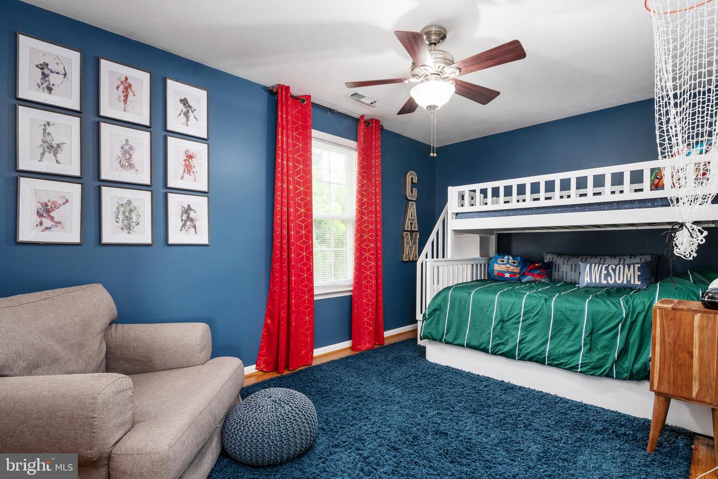 Bedroom with a white loft bed, green bedding, blue walls, and a gray sofa.