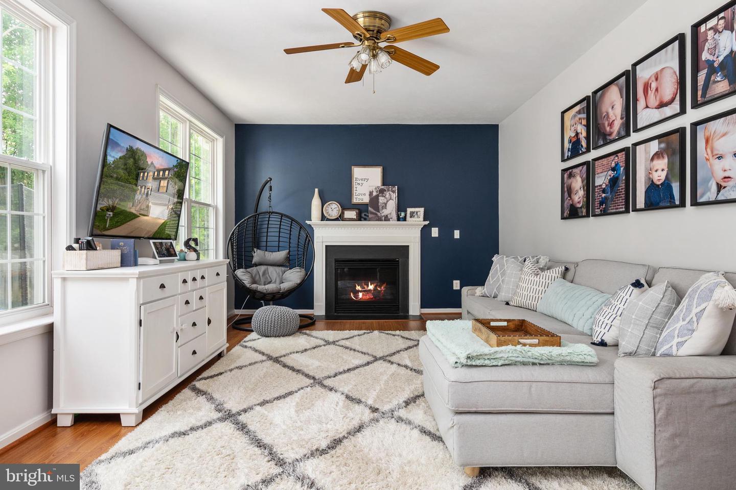Living room with a navy fireplace wall, gray sectional, hanging chair, and tall windows.