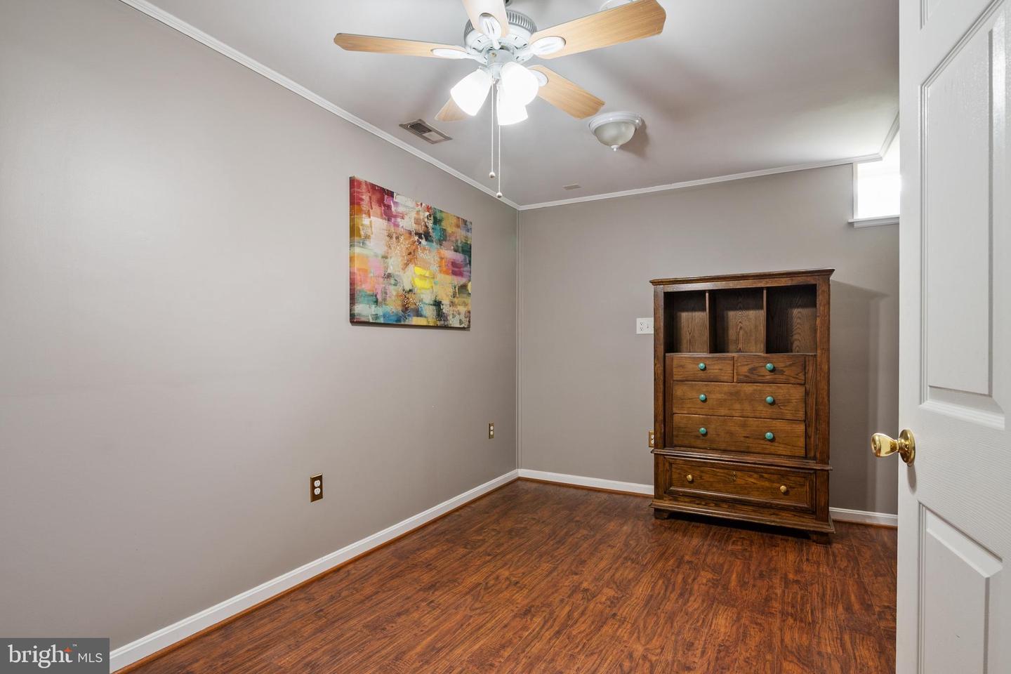 Bedroom with dark wood floors, gray walls, a ceiling fan, and a wooden dresser.