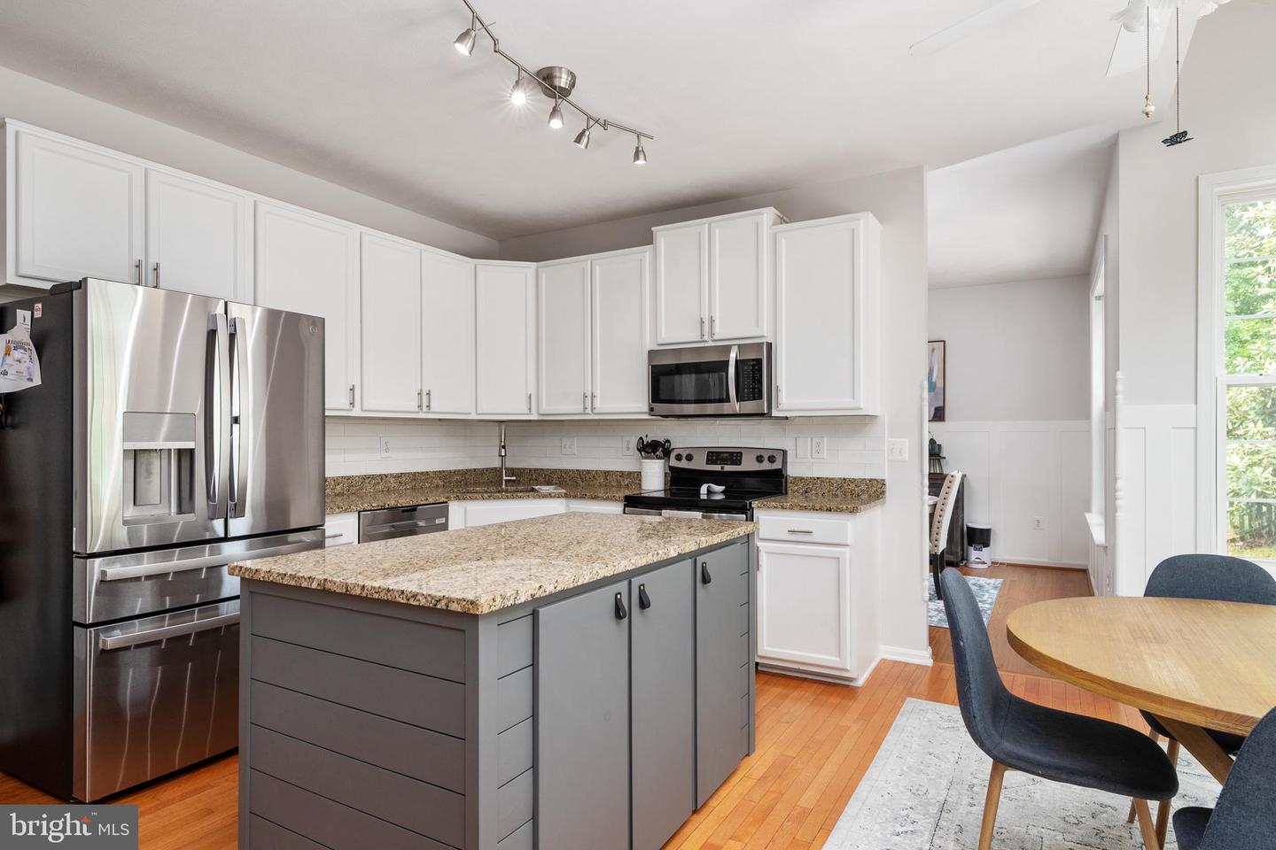 Kitchen with a gray island, granite counters, stainless steel appliances, and adjoining dining area.