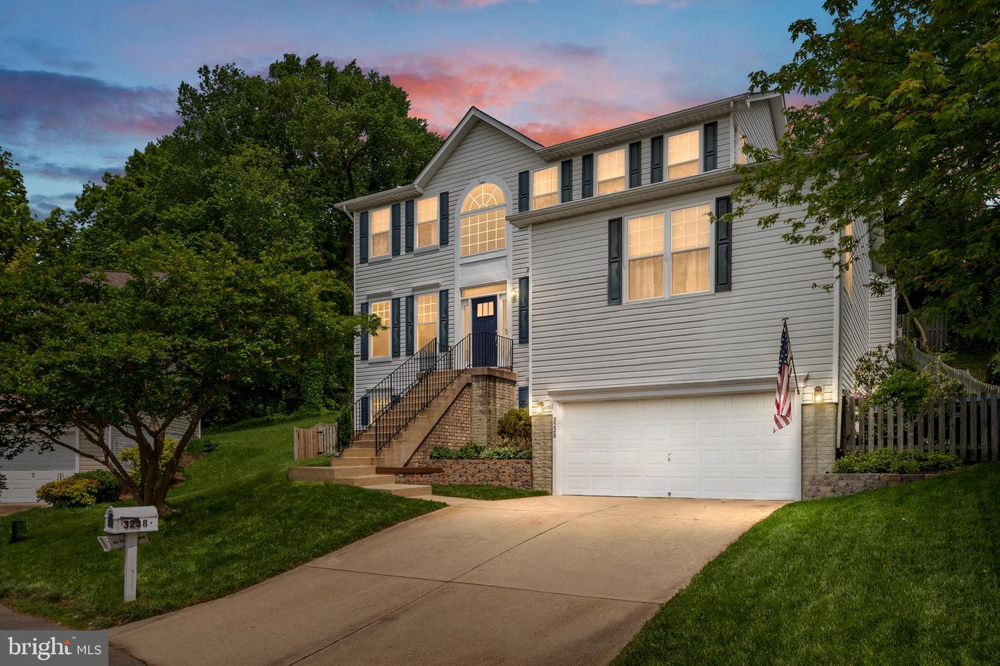 Two-story gray house with an arched window, raised entry steps, and an attached two-car garage at dusk.