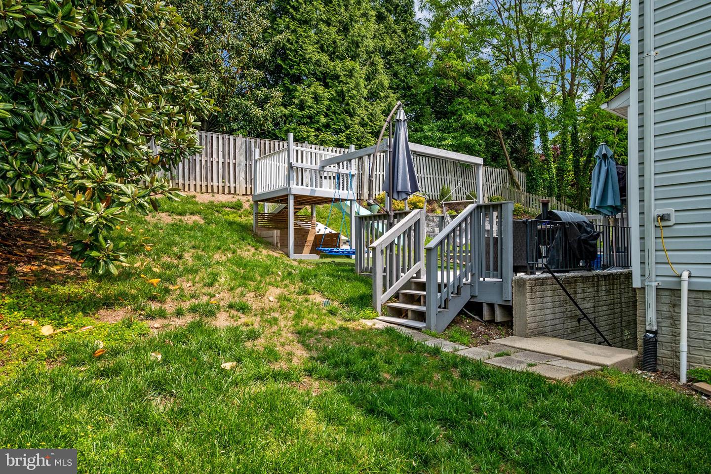Backyard with a raised deck and swing above a lower deck with patio furniture and grill.