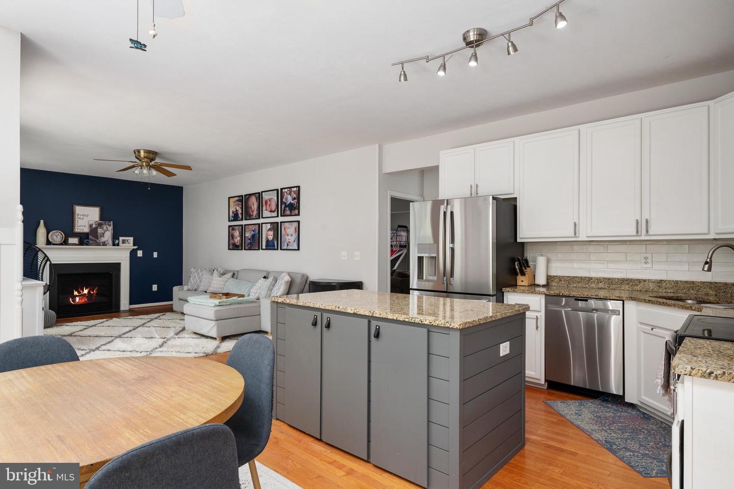 Open kitchen and living room with a gray island, stainless steel appliances, and a fireplace.