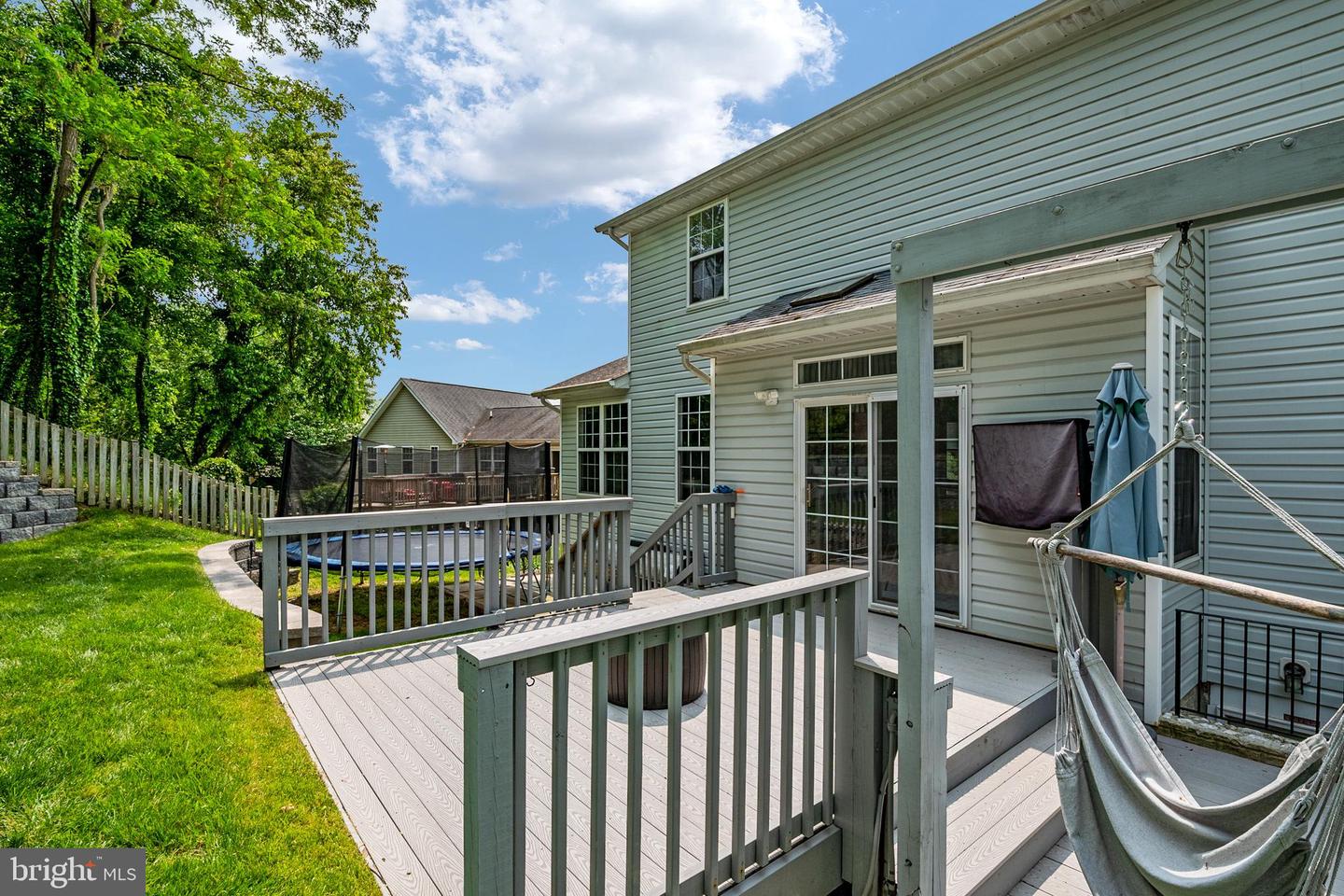 Rear deck with a hammock overlooks a grassy yard and trampoline.