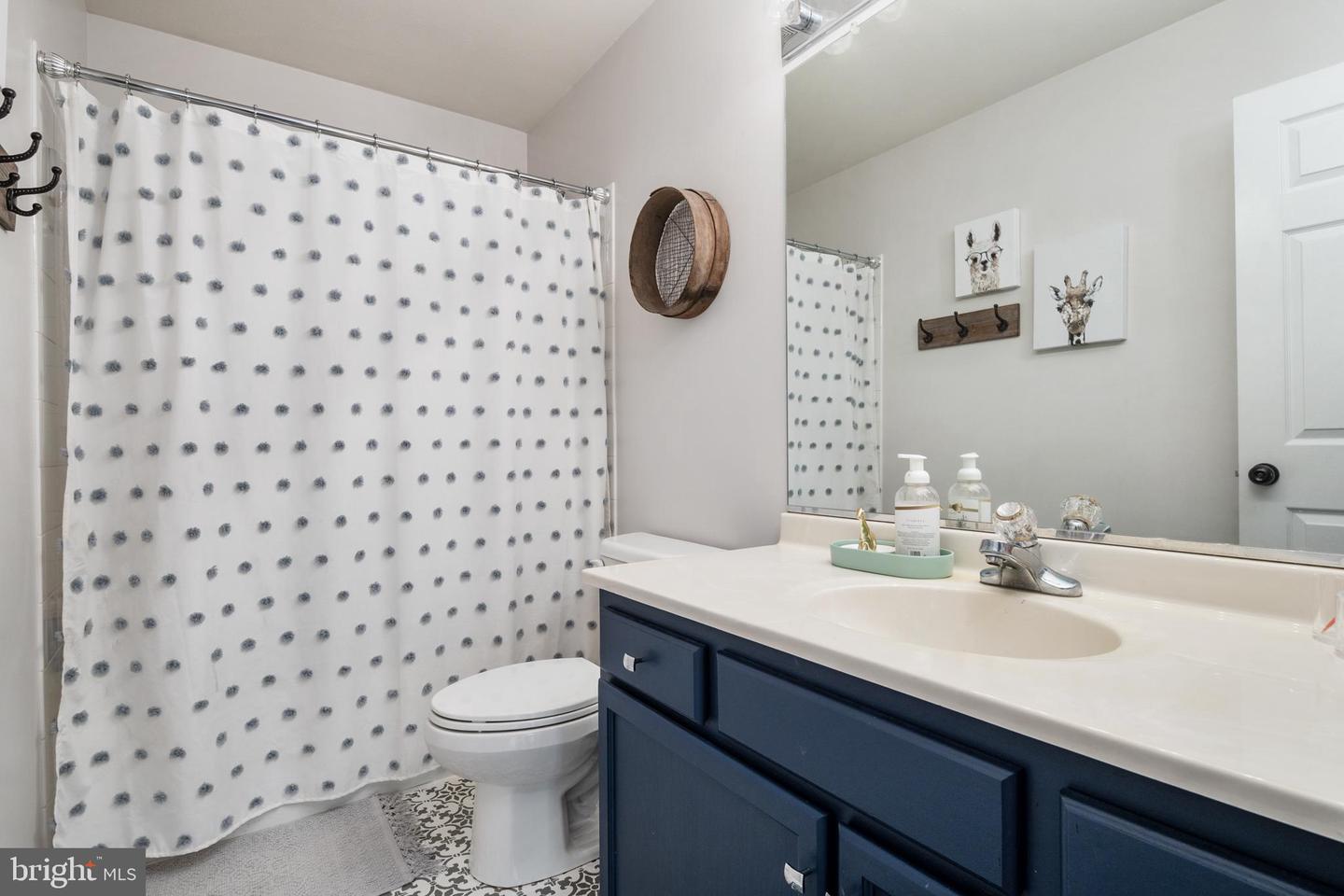 Bathroom with a navy vanity, large mirror, and dotted shower curtain.