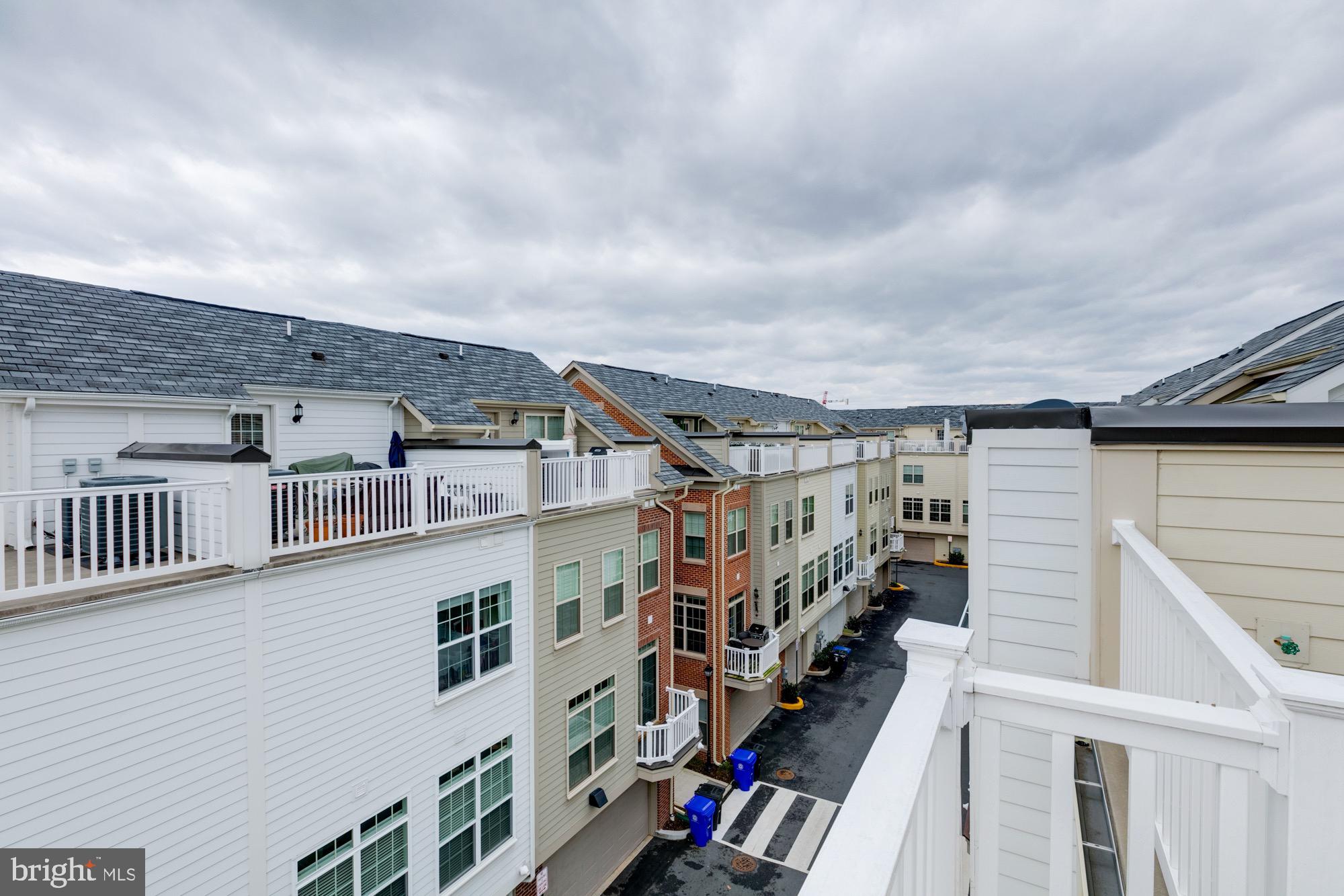 Attached townhouses viewed from above, with rooftop decks and a shared paved lane.