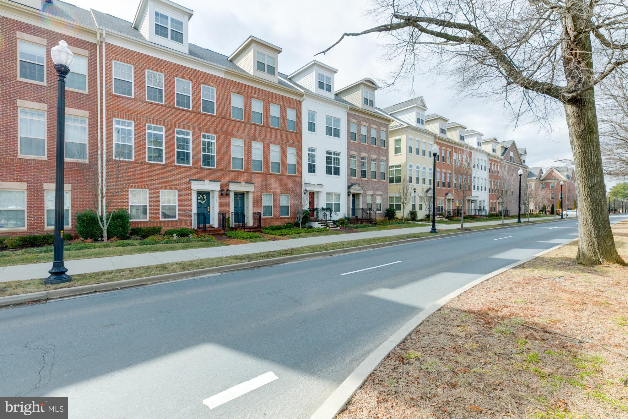 Attached brick townhouses with dormer windows and front stoops along a tree-lined street.