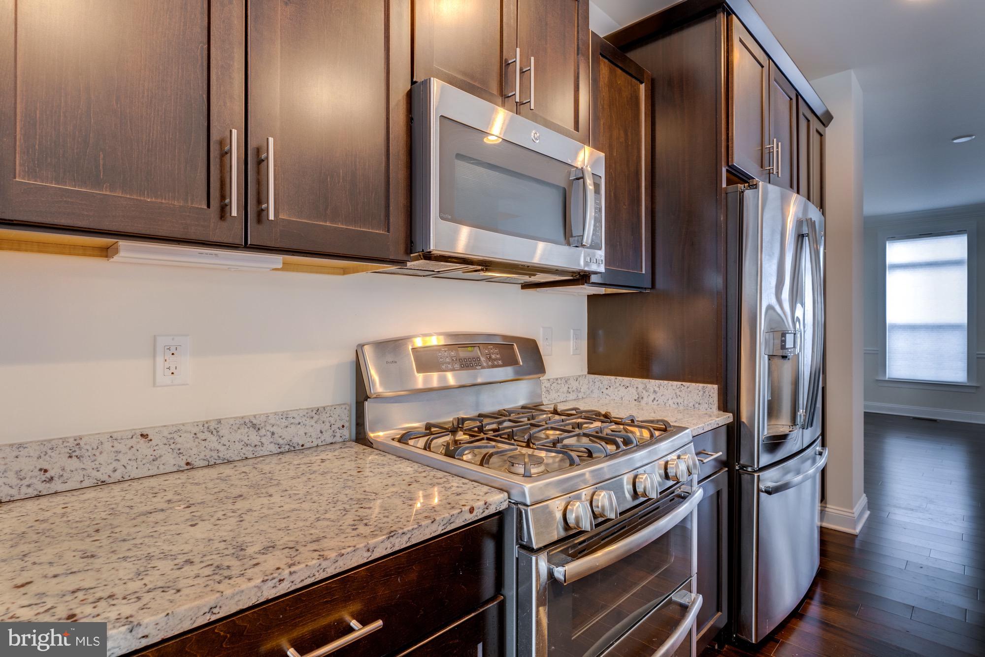 Kitchen with dark wood cabinets, granite counters, and stainless-steel appliances.