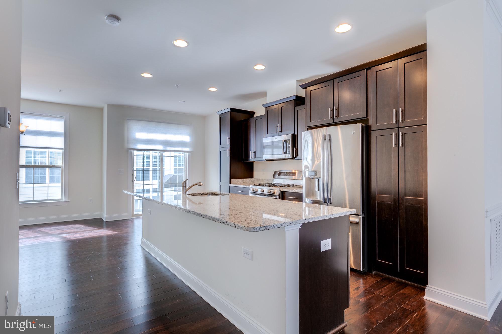 Kitchen with a granite island, dark wood cabinets, stainless steel appliances, and adjoining dining area.