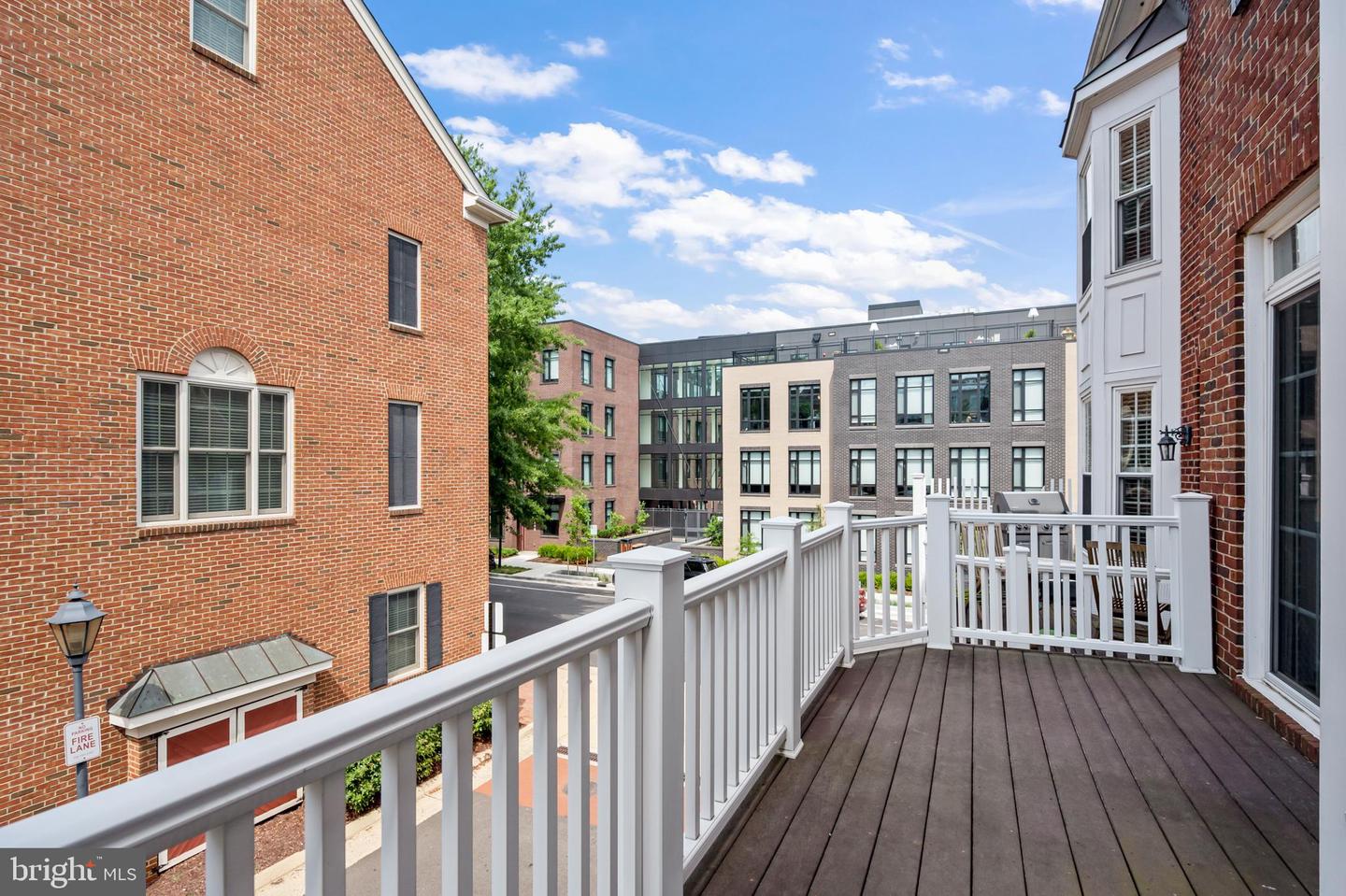 Elevated deck with white railings overlooking brick homes and modern urban buildings.