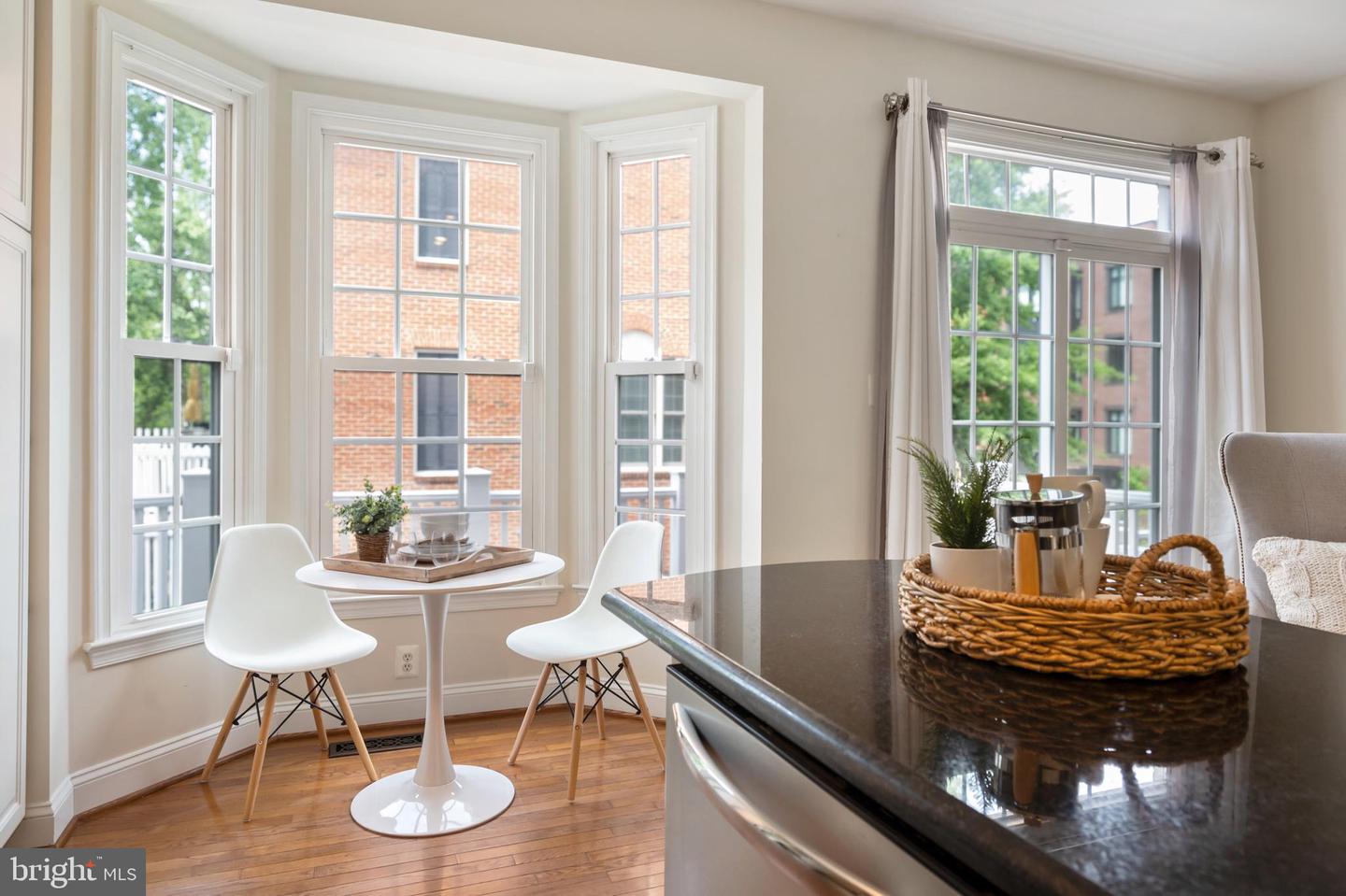Kitchen breakfast nook with a round table, tall windows, and a dark stone island.