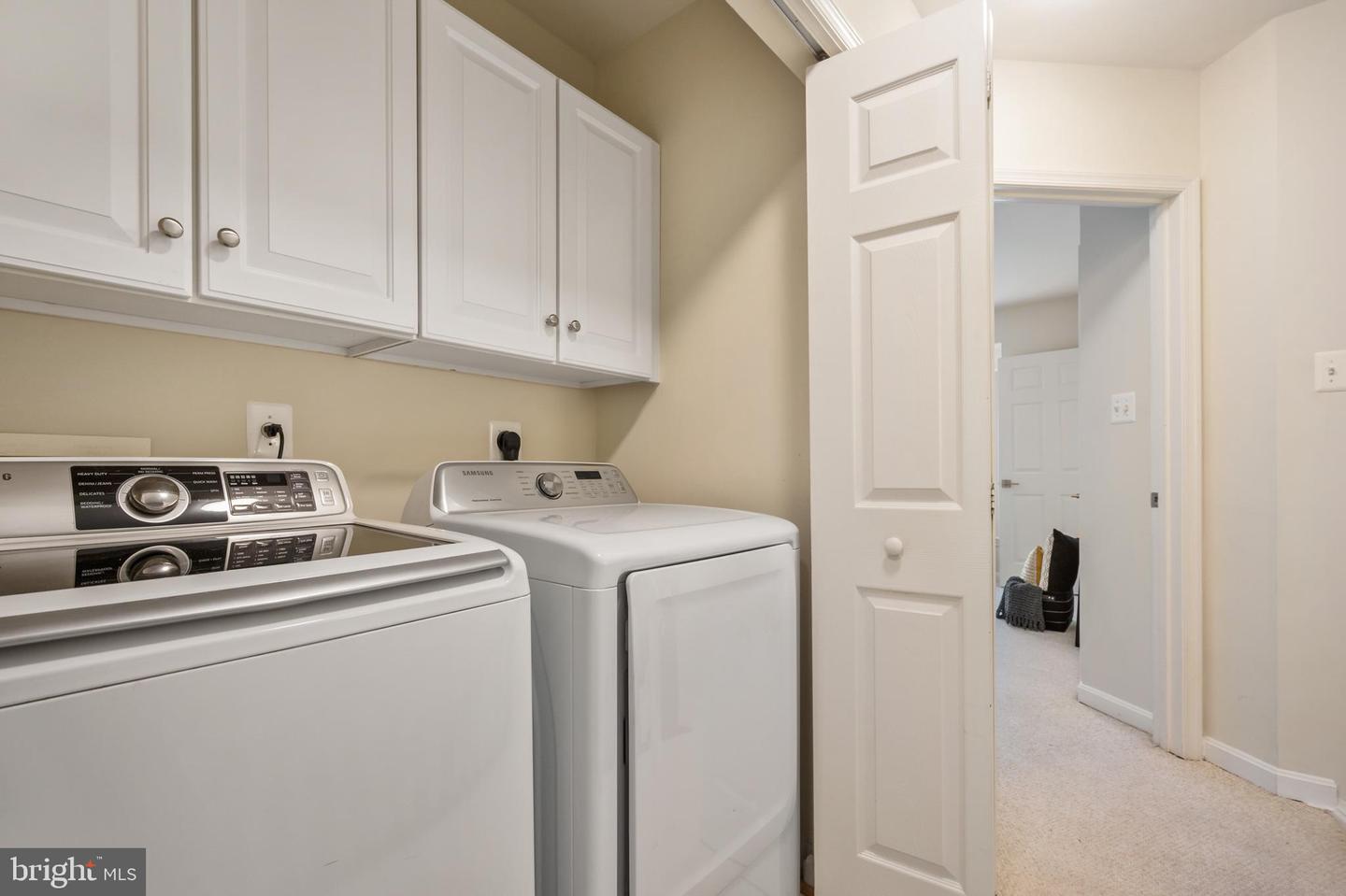 Laundry room with washer, dryer, and white wall cabinets.