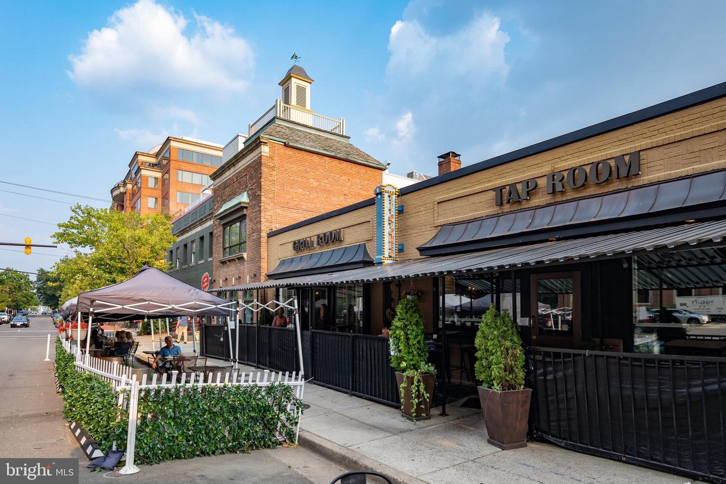 Brick restaurant with a covered outdoor patio, planters, and Tap Room and Grill Room signs.