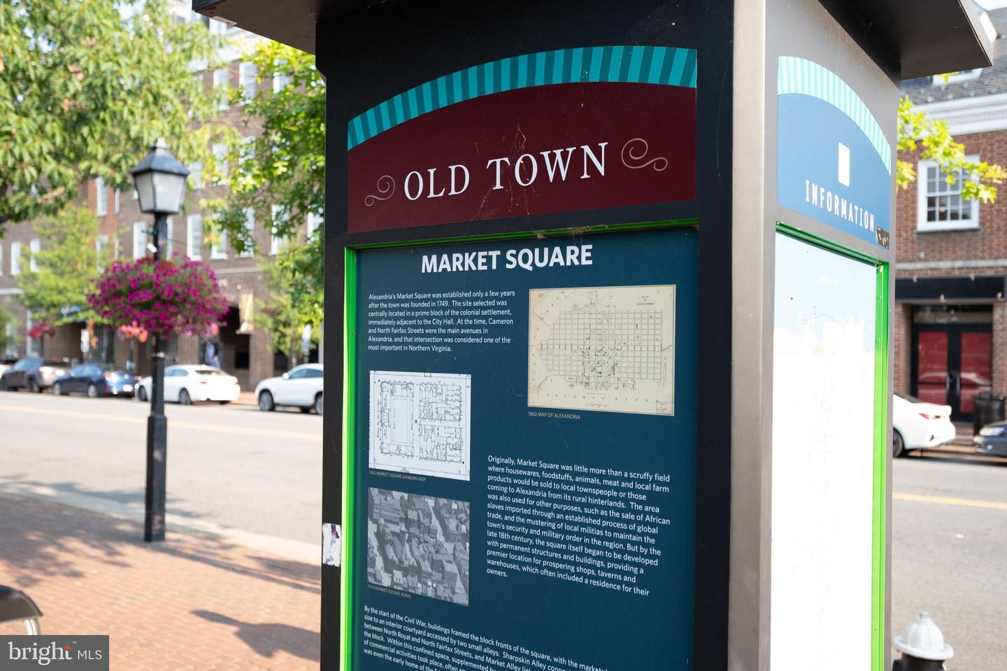 Old Town Market Square information kiosk with historic maps on a tree-lined Alexandria street.