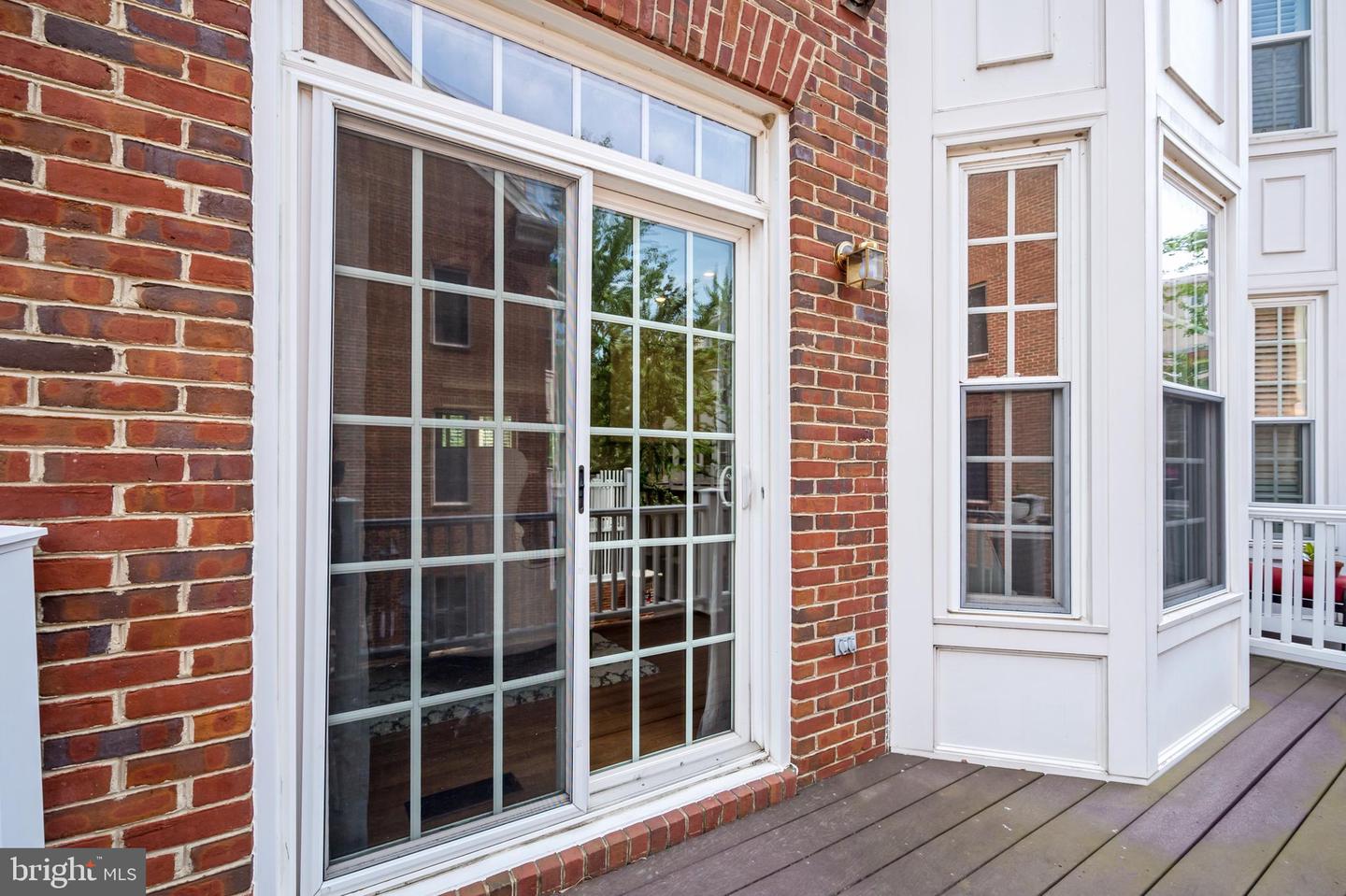Brick townhouse exterior with white-trimmed glass doors opening onto a wood deck.