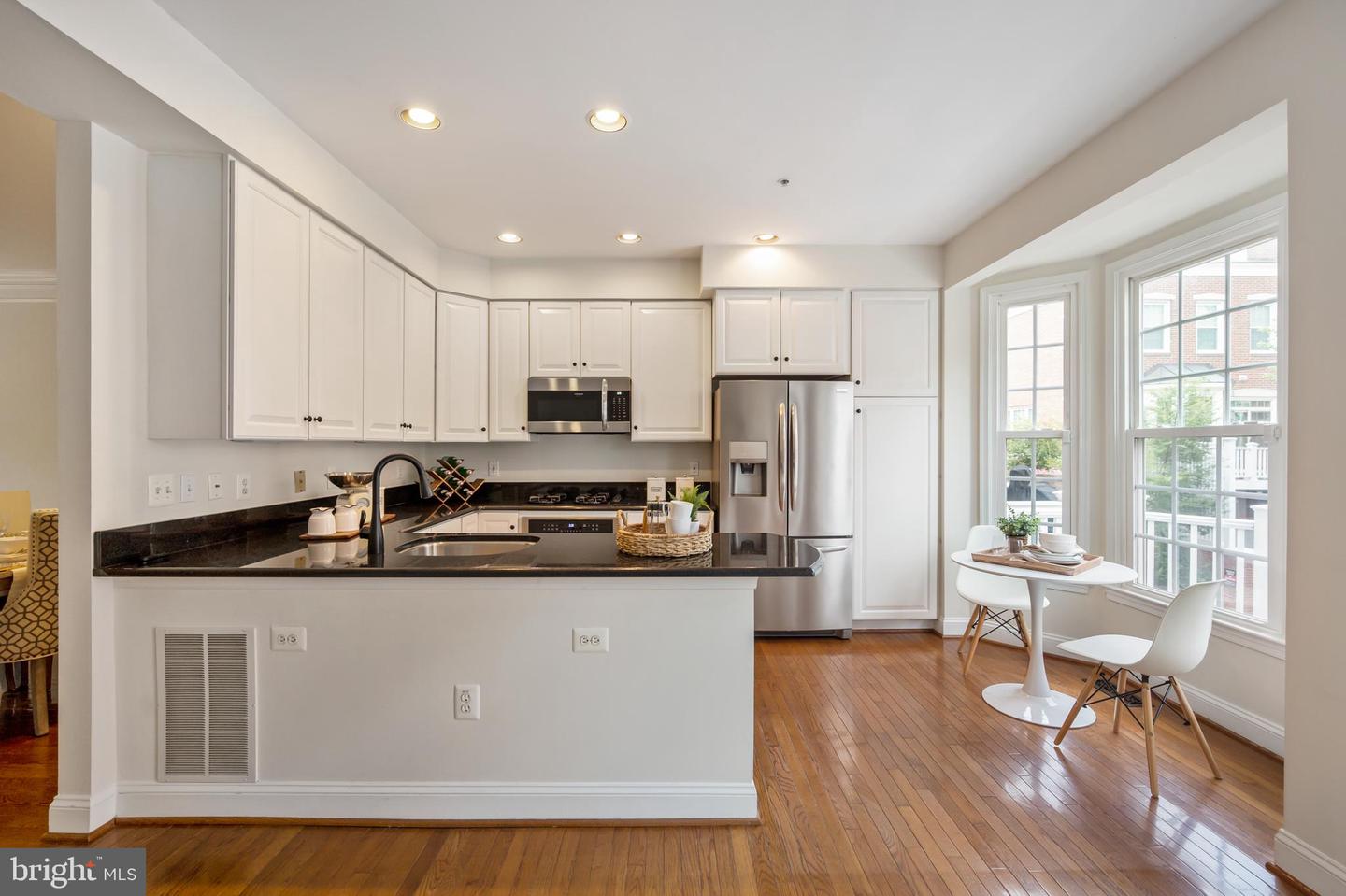 Kitchen with white cabinets, black countertops, stainless steel appliances, and a window-side breakfast nook.