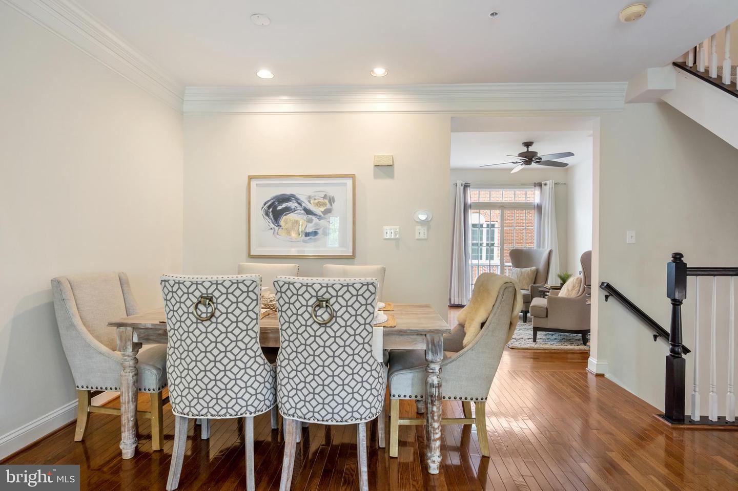 Dining room with a wooden table, patterned chairs, hardwood floors, and an adjoining sitting area.
