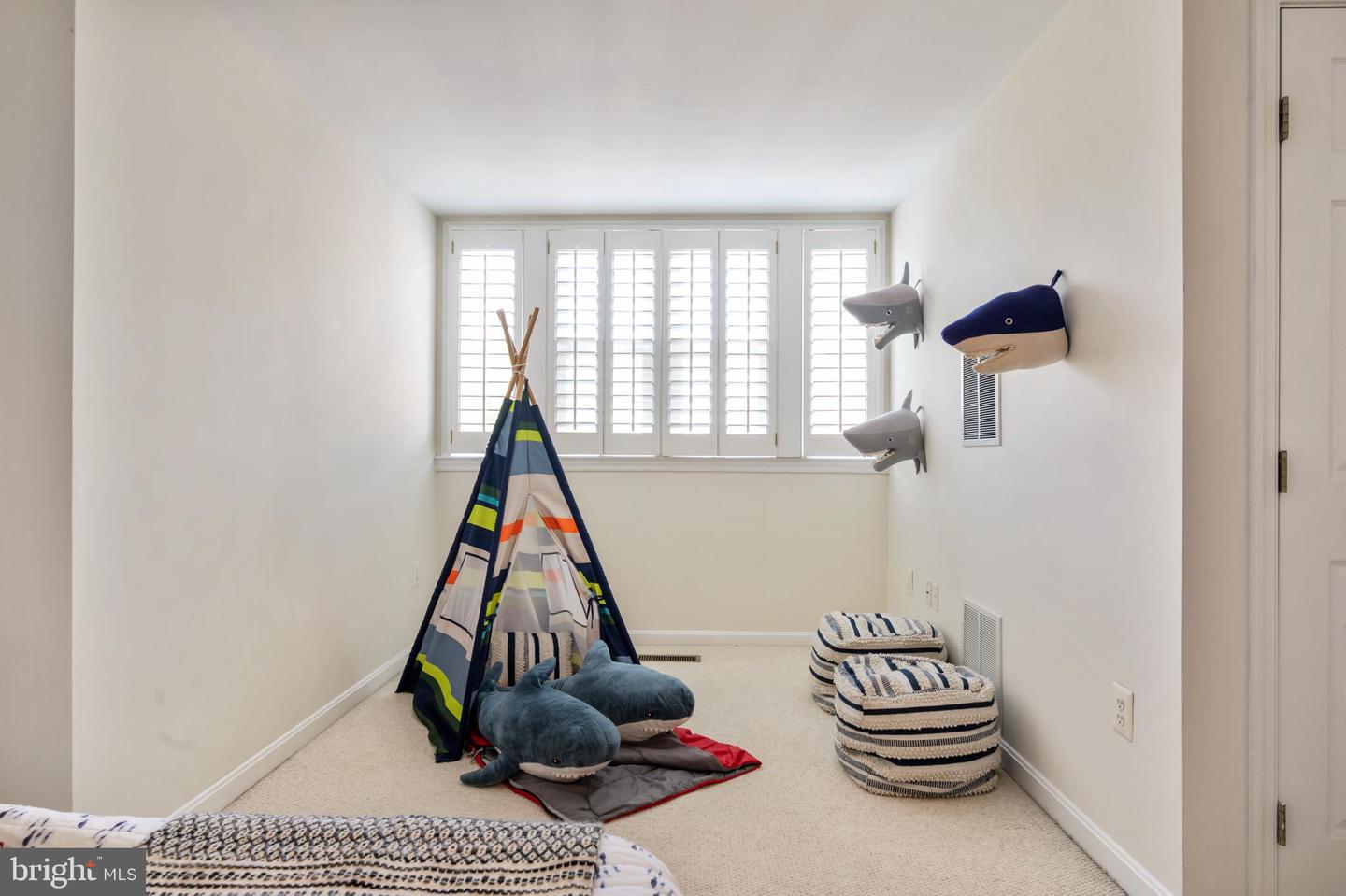 Children’s bedroom with a colorful teepee tent, plush sharks, and striped cushions.