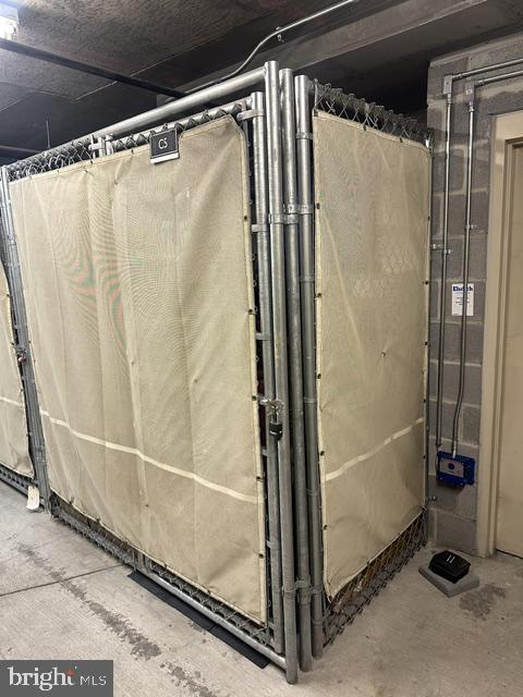 Metal storage cage with beige fabric panels in a concrete interior.