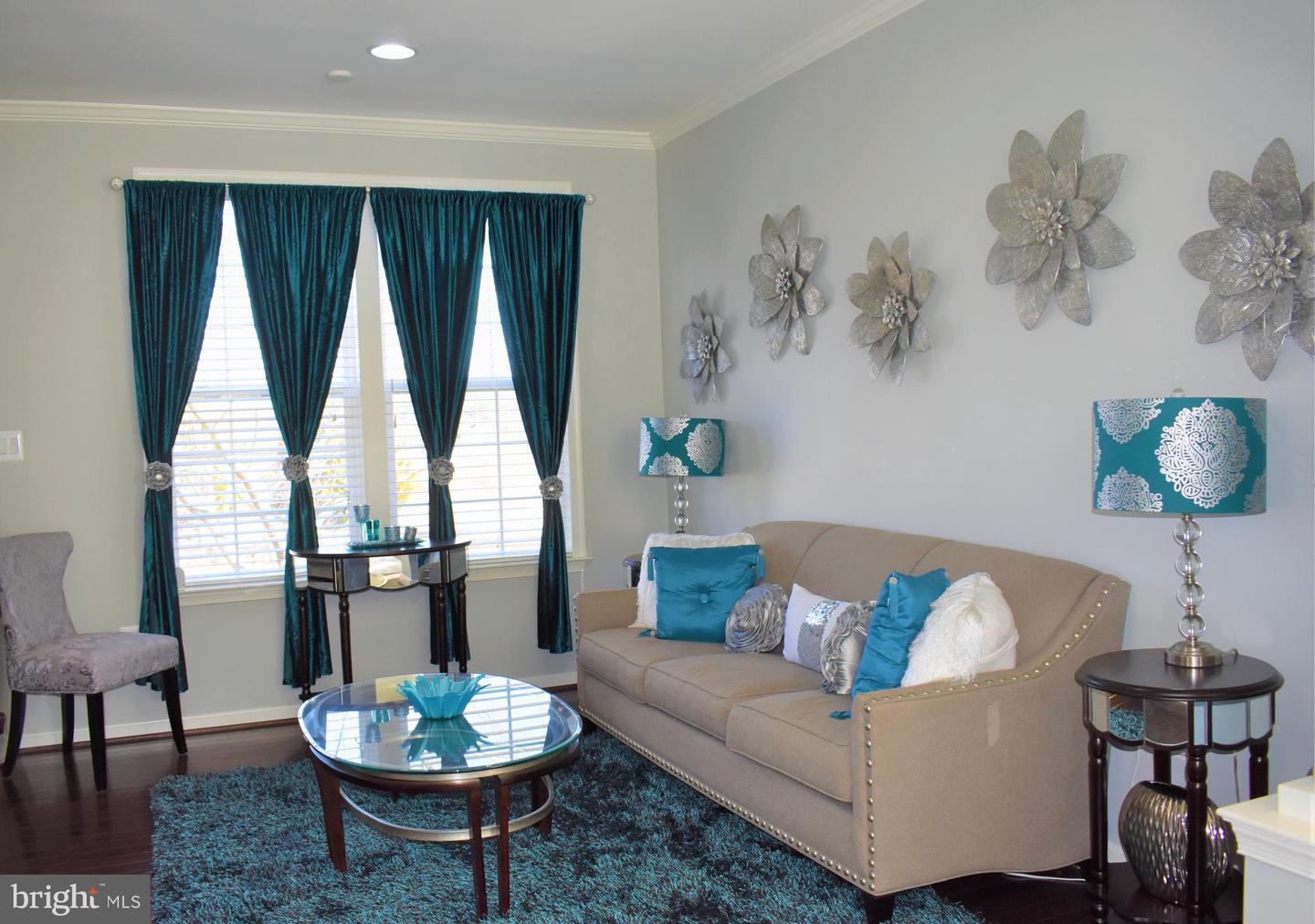 Living room with a beige sofa, teal curtains and accents, and metallic flower wall decor.
