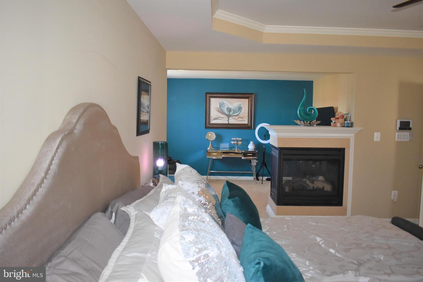 Bedroom with an upholstered bed, teal accent wall, and fireplace.
