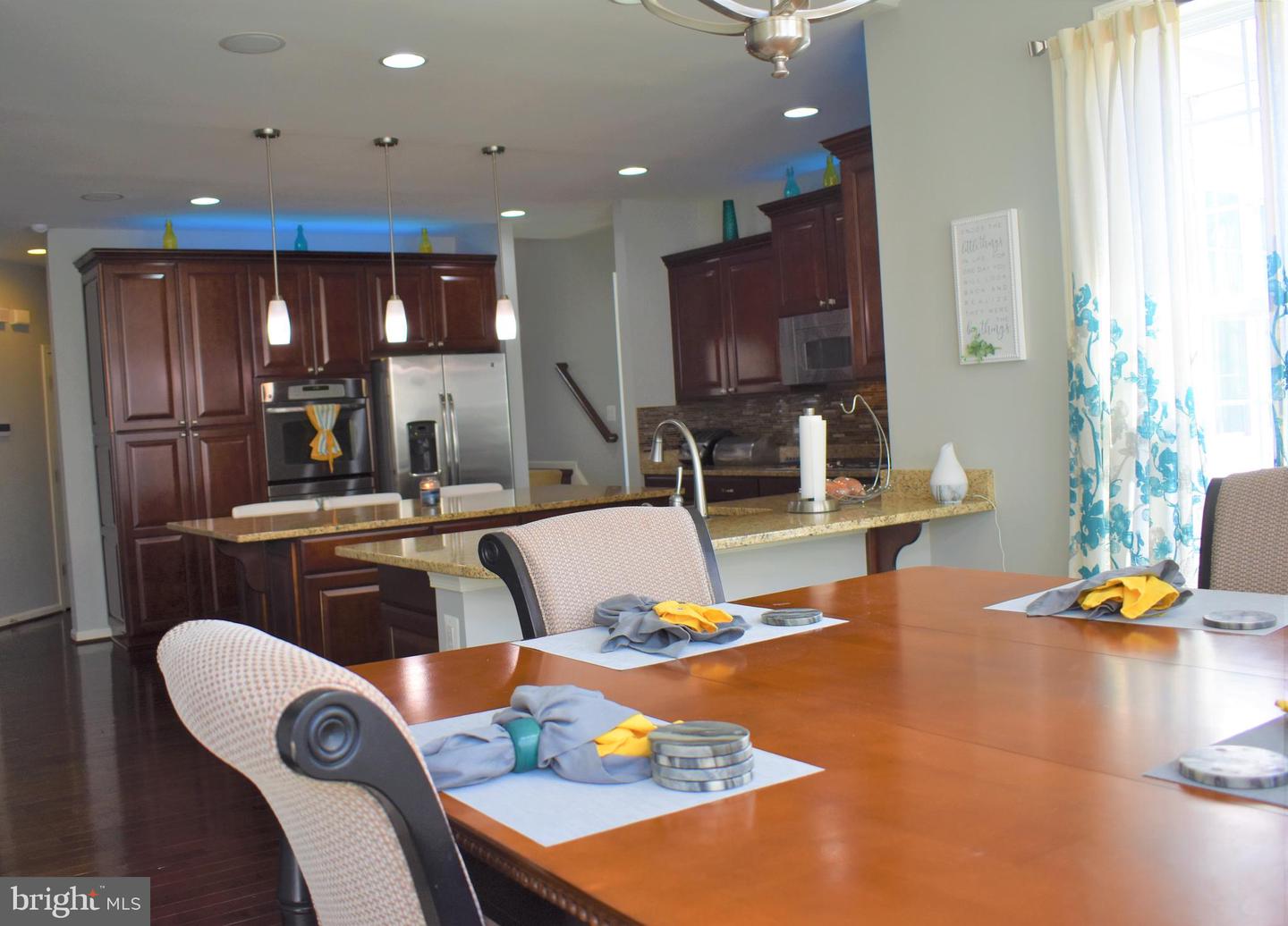 Kitchen and dining area with dark cherry cabinets, granite counters, and a large wooden table.