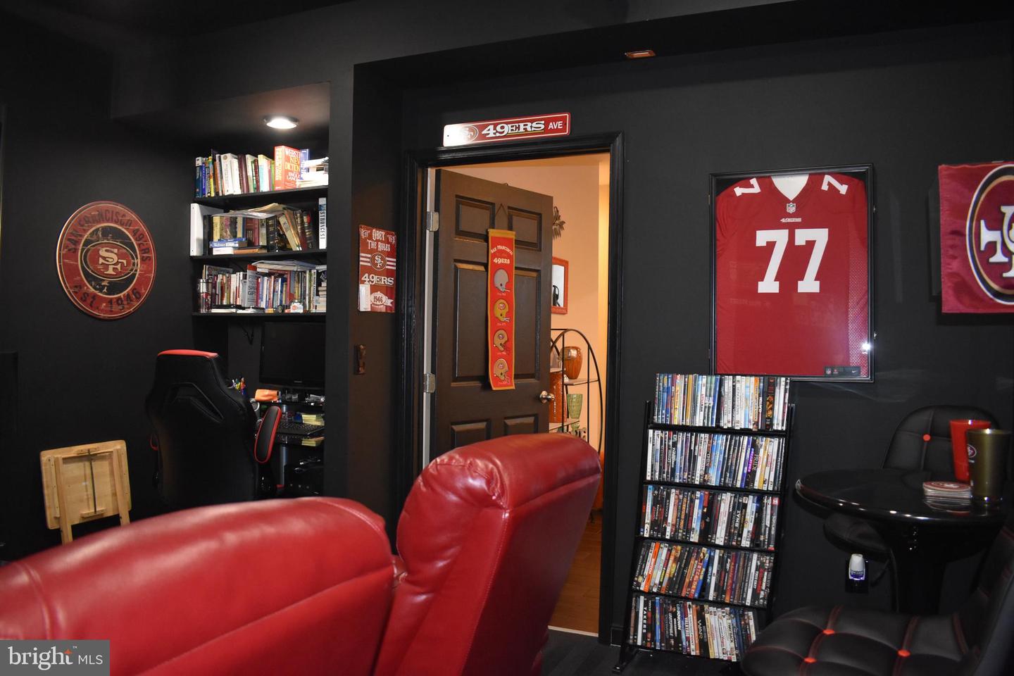 Home theater with red leather seating, dark walls, and San Francisco 49ers memorabilia.