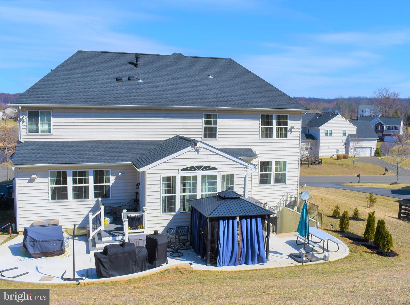 Rear of a two-story home with a large patio and curtained gazebo.