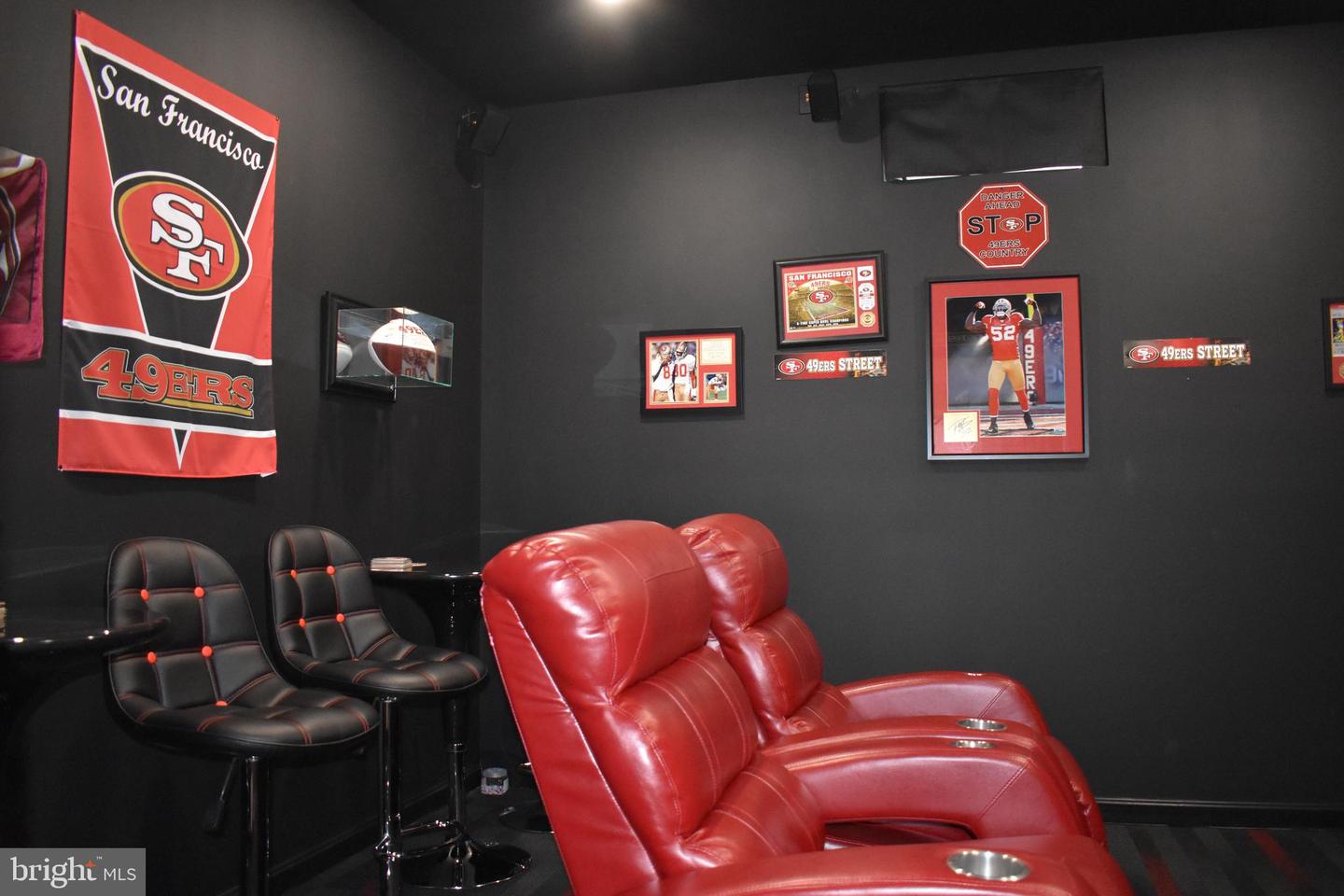 Home theater with red leather recliners, bar stools, and San Francisco 49ers memorabilia.