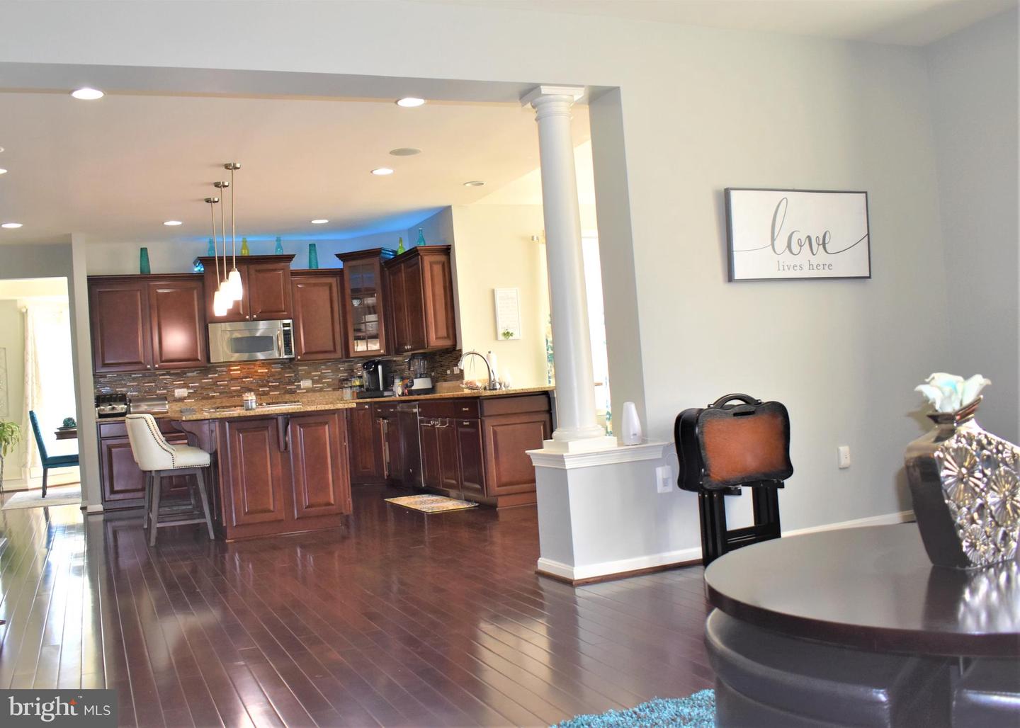 Kitchen with cherry cabinets, mosaic tile backsplash, and dark wood floors, opening into a dining area.