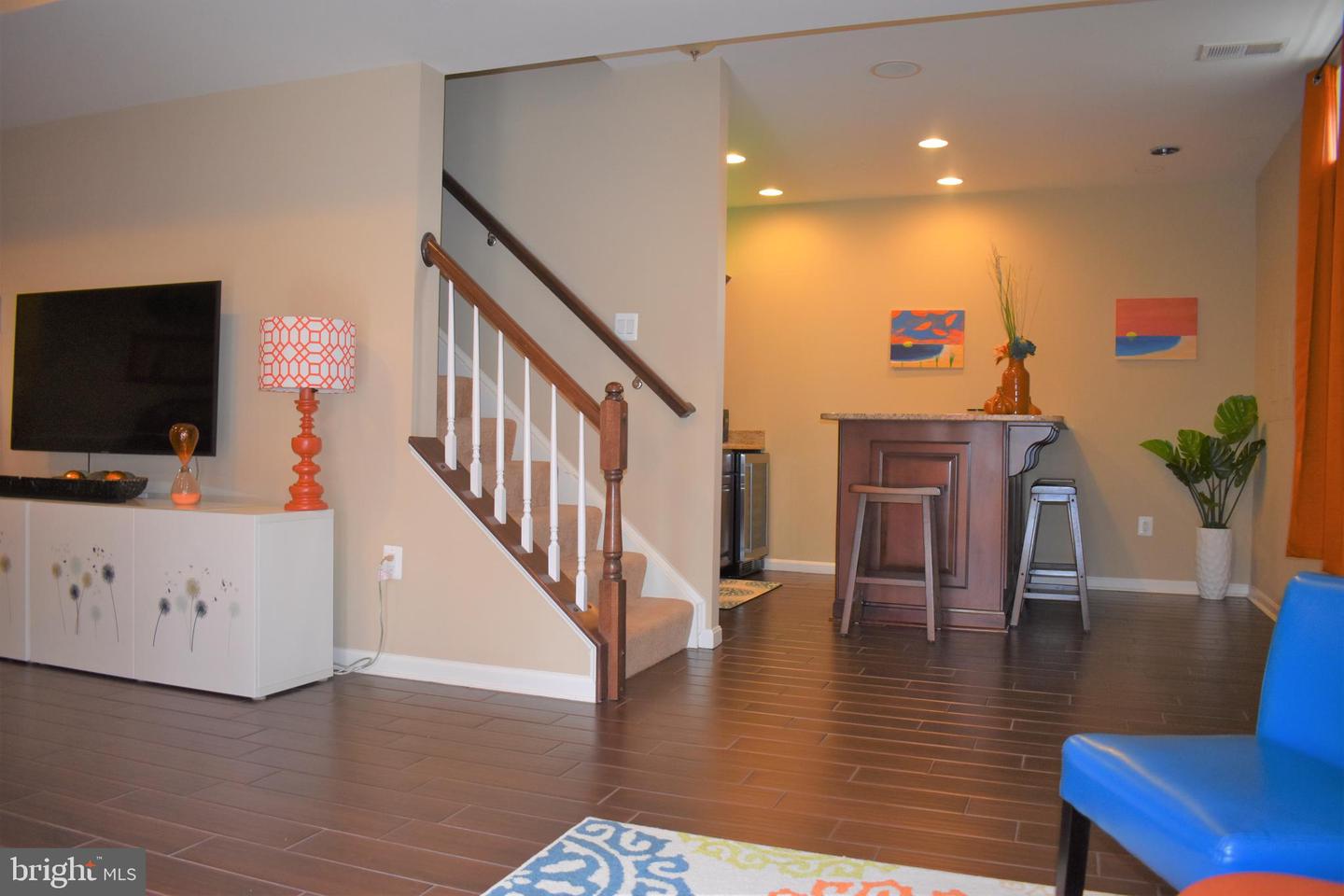 Living room with a staircase, television console, and raised bar counter with stools.