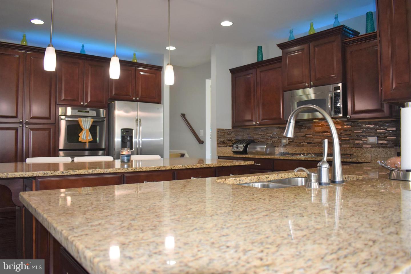 Kitchen with cherry cabinets, stainless steel appliances, mosaic tile backsplash, and a large granite island.