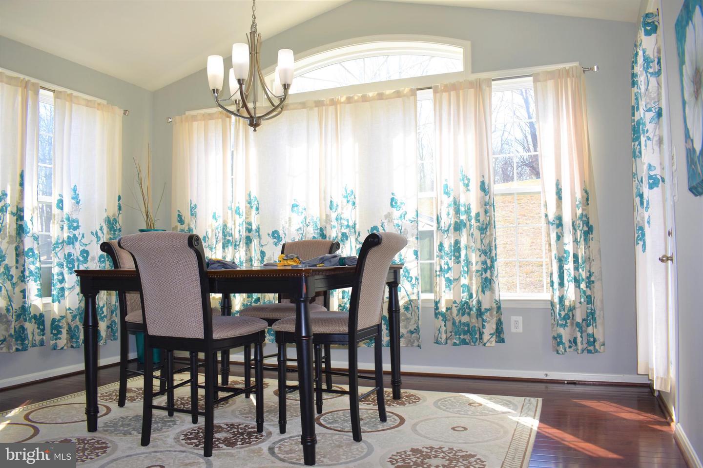 Dining room with a dark wood table, blue floral curtains, and a chandelier.