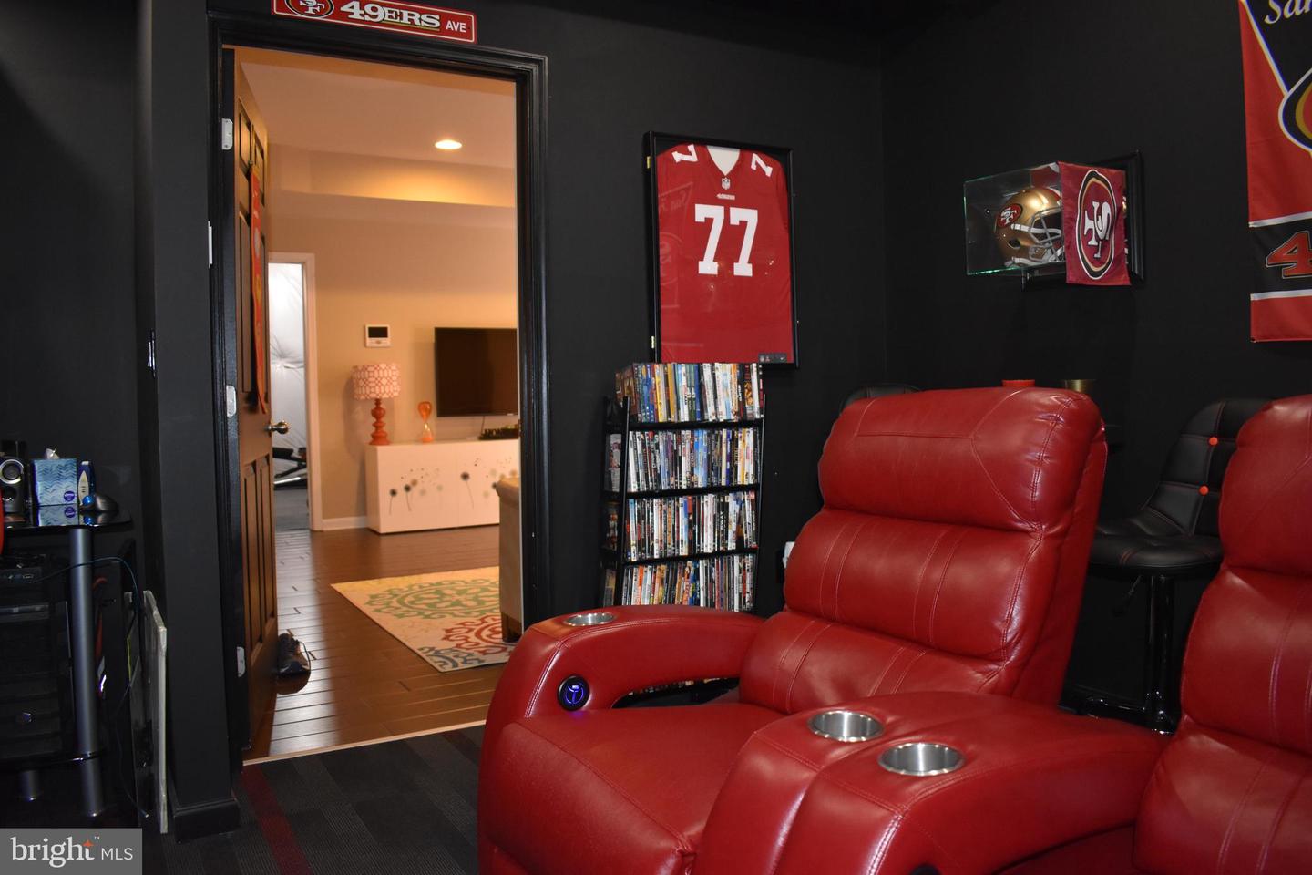 Home theater with red leather recliners, black walls, and San Francisco 49ers memorabilia.