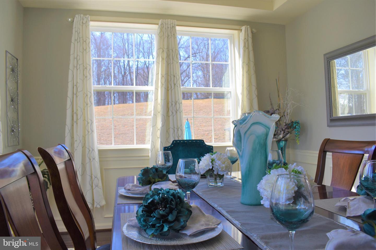 Dining room with a set table, teal accents, dark wood chairs, and a large window.