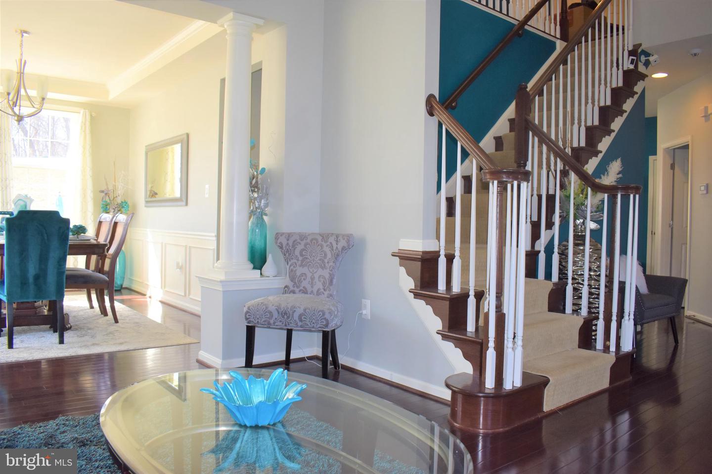 Furnished interior with a carpeted staircase, dark wood railings, teal walls, and glass coffee table.