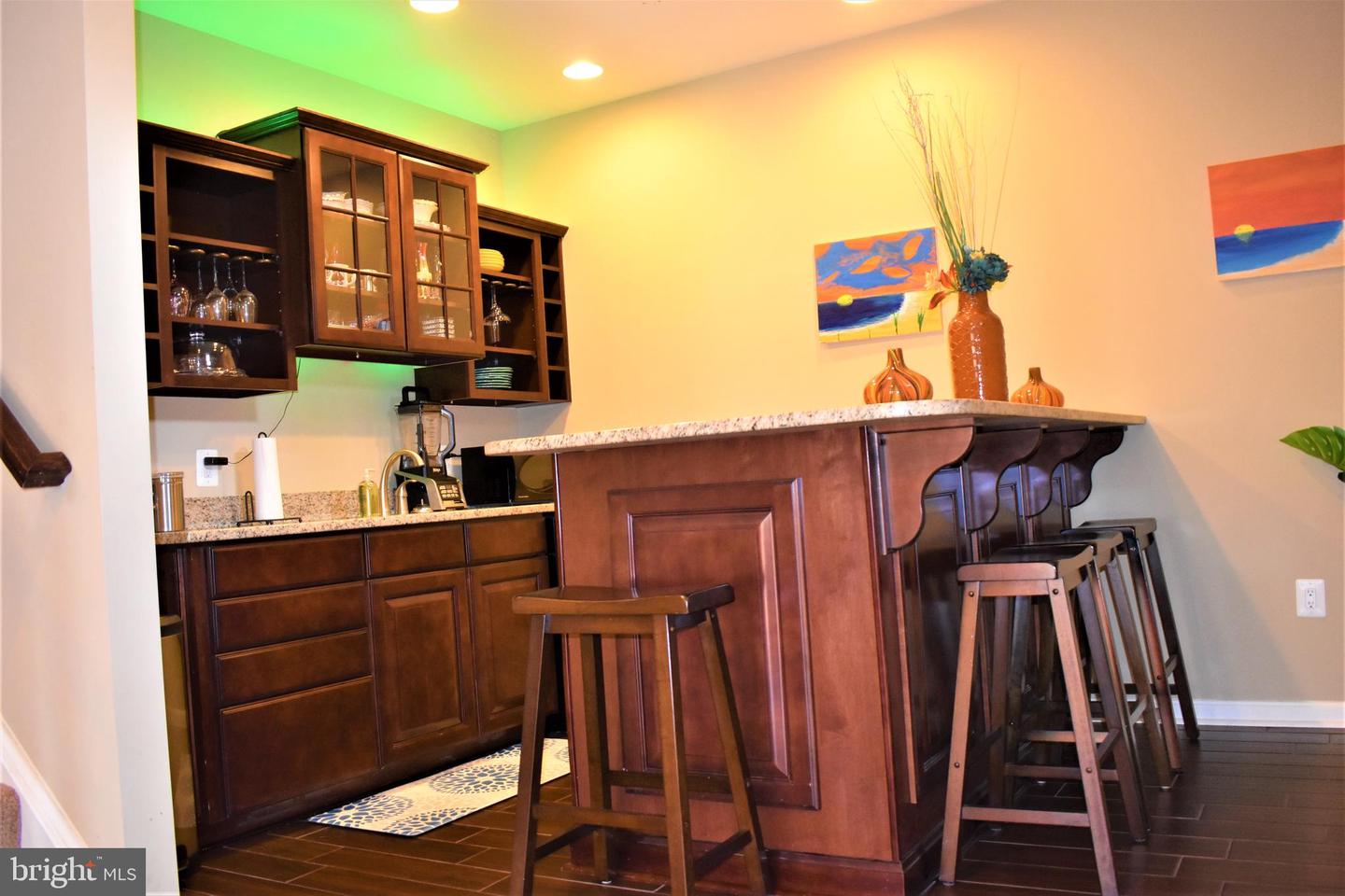 Home bar with dark wood cabinets, granite counters, and a raised seating bar with stools.