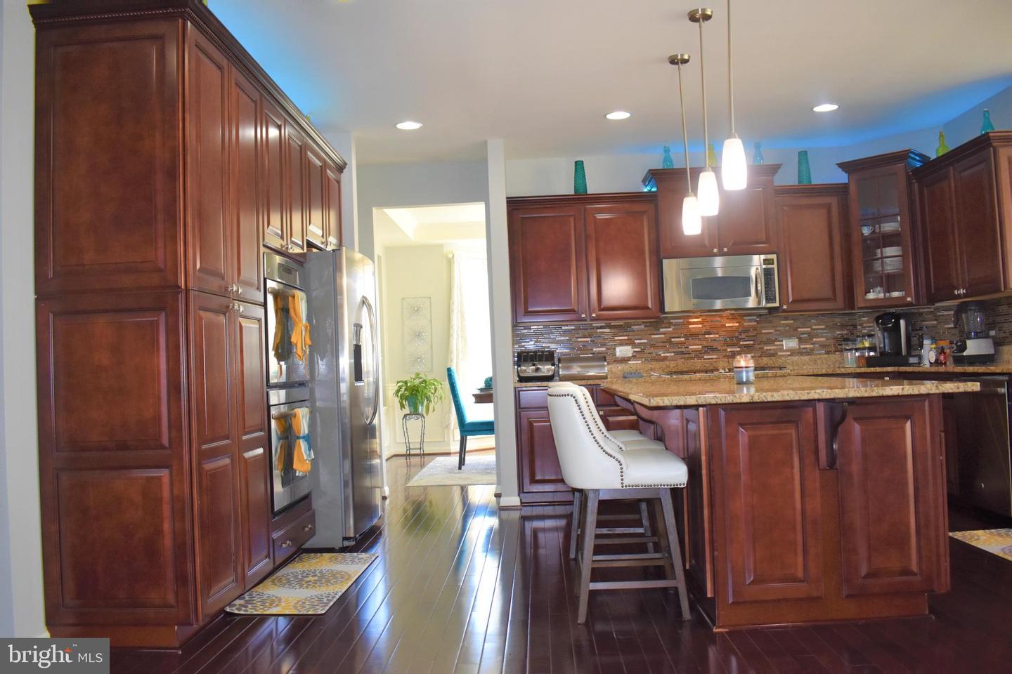 Kitchen with dark wood cabinetry, stainless steel appliances, and a granite island with bar seating.