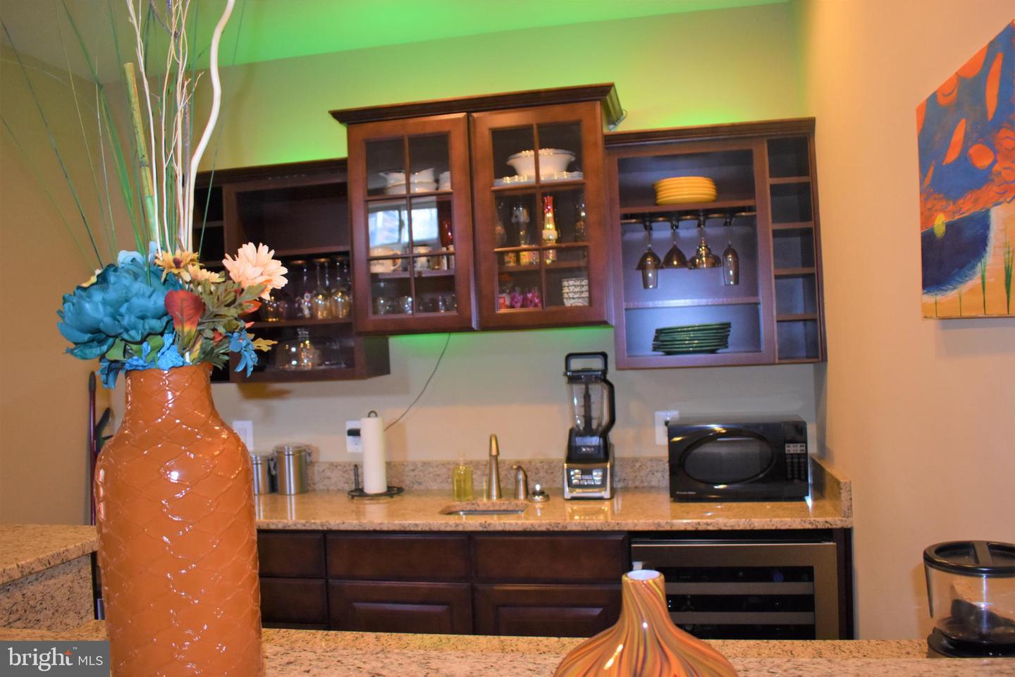 Kitchen with dark wood display cabinets, granite counters, and a large vase of flowers.